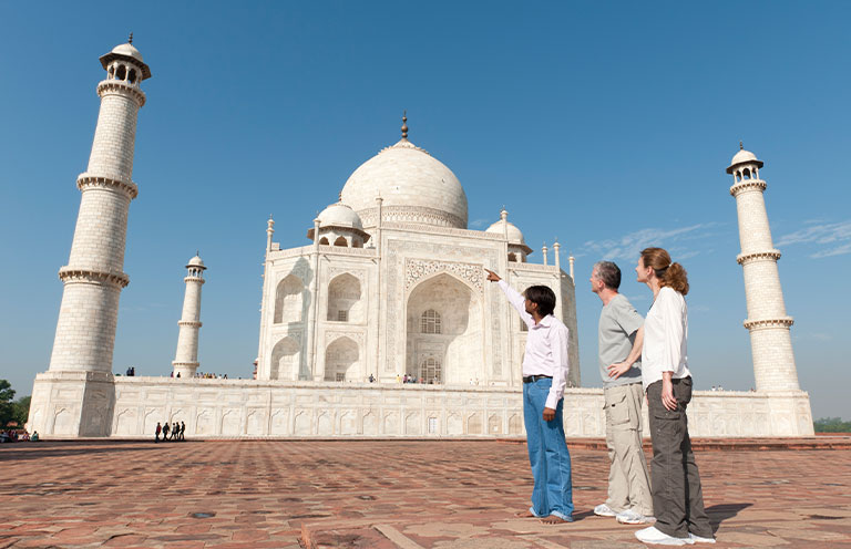 tour guide, man and woman looking at taj mahal