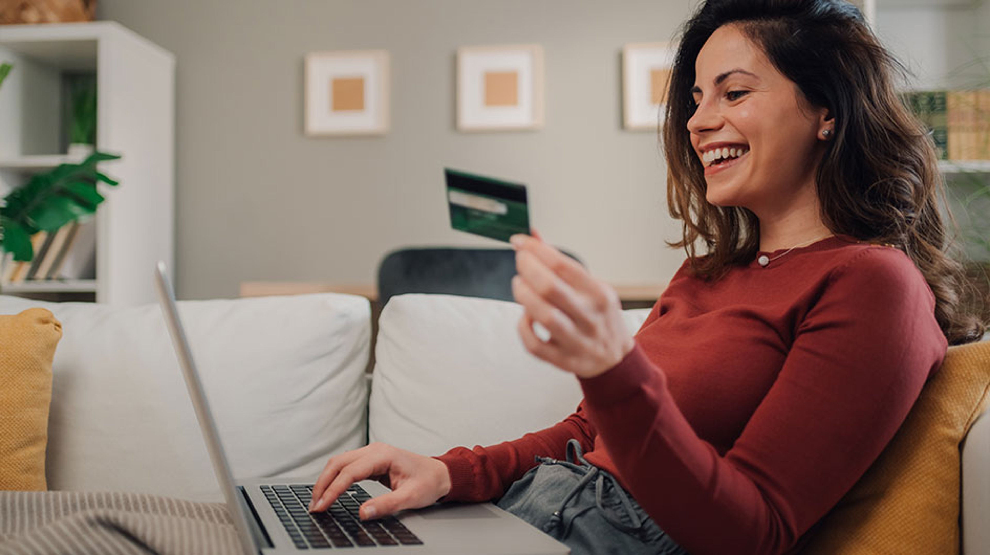 woman smiling and  holding credit card  while using laptop