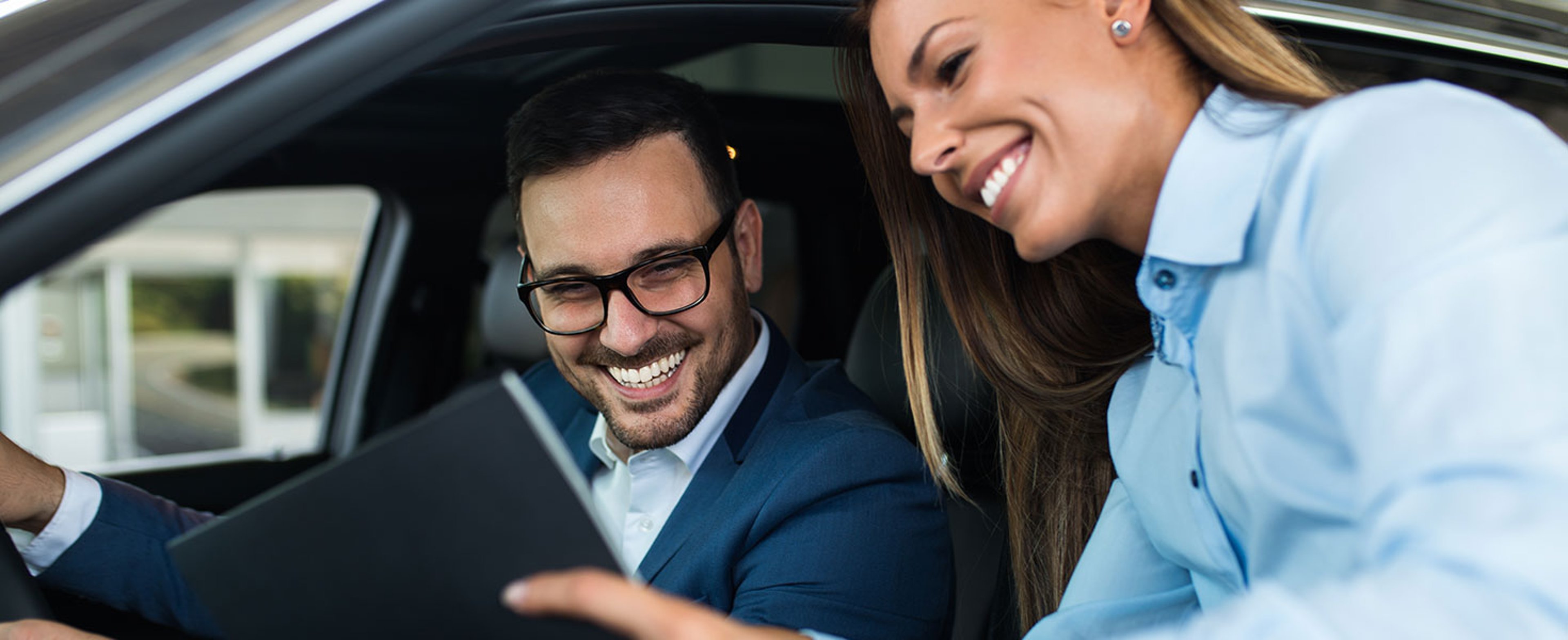 Saleswoman at the dealership showroom talking with customer and helping him to choose a new car for himself. By hedgehog94