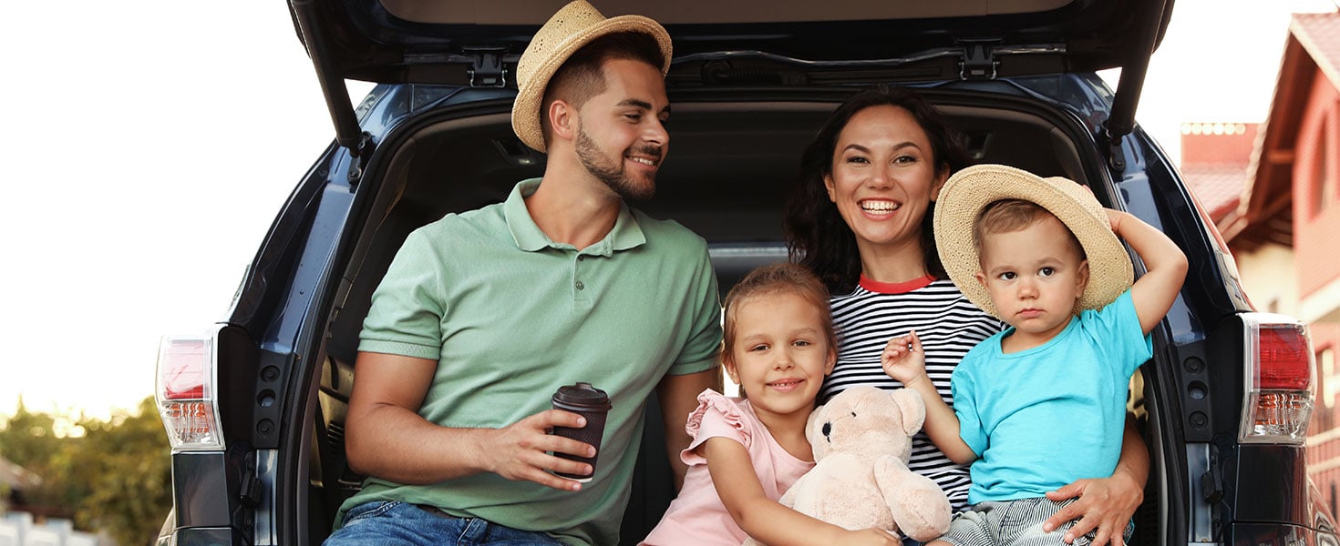 family sitting in suv trunk