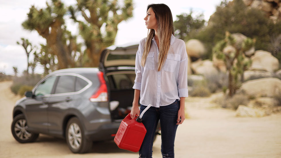 woman holding empty gas canister in front of car