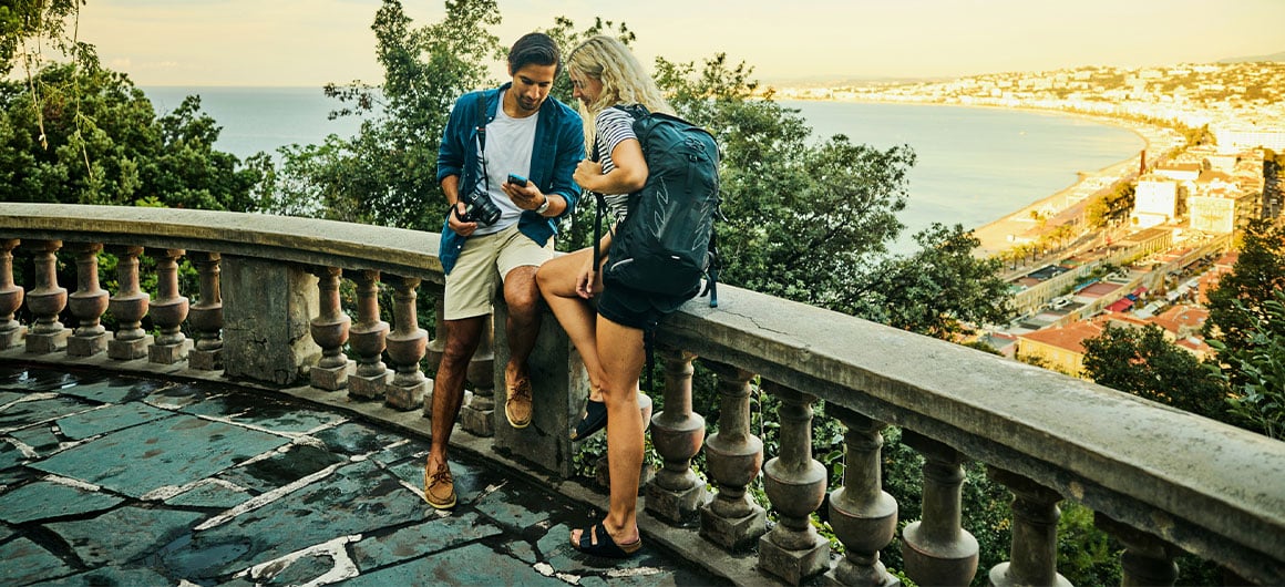 man and woman sitting on balcony ledge looking at phone