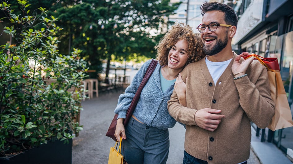 man and woman holding shopping bags on street