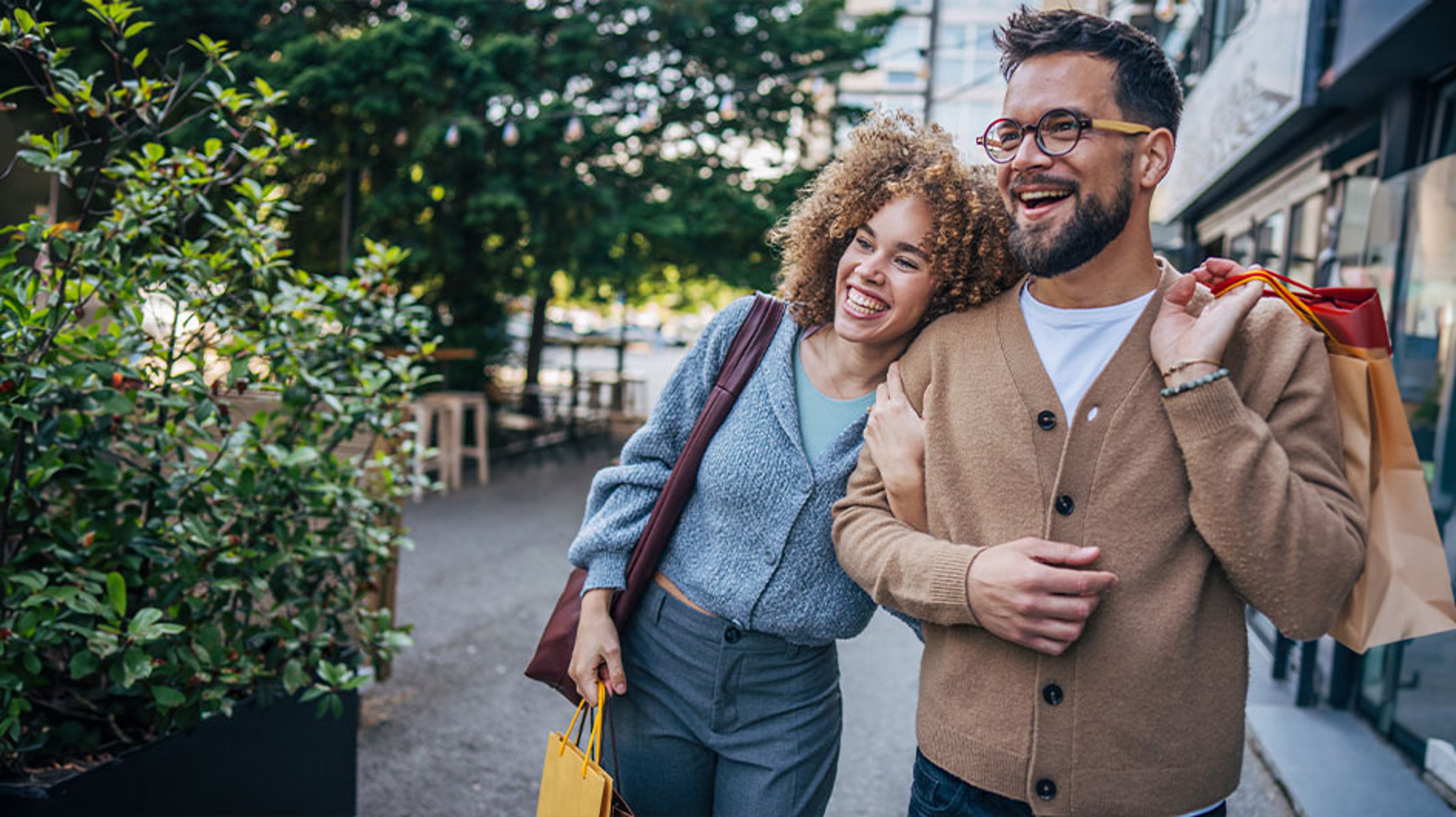 man and woman holding shopping bags on street