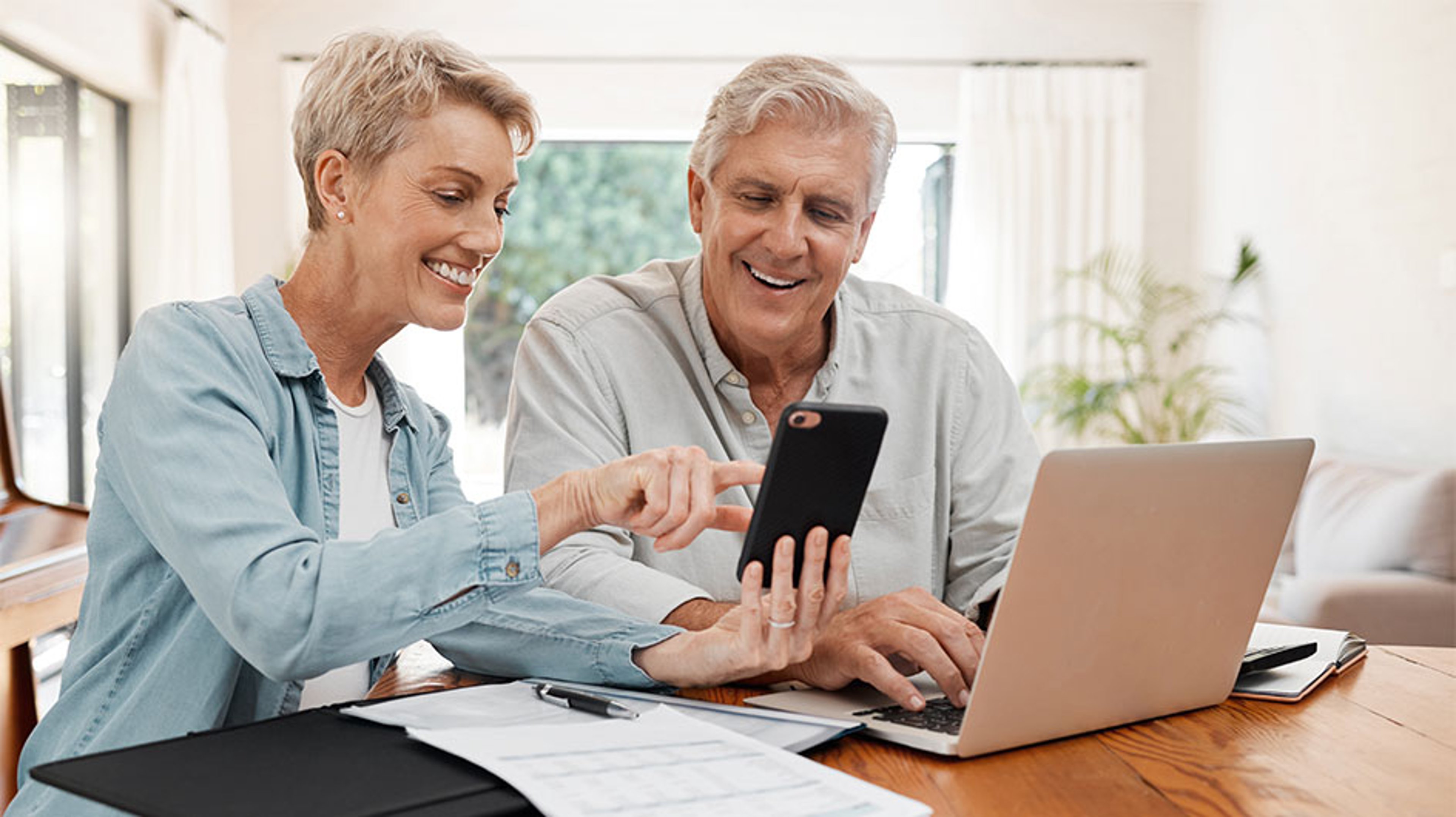 man and woman looking at phone and laptop