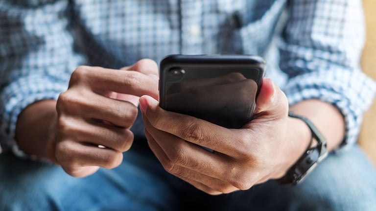 Young casual Businessman holding and using smartphone for sms messages, hipster man typing touchscreen cell phone in the cafe. business, lifestyle, technology and Social media network concept. By Jo Panuwat D