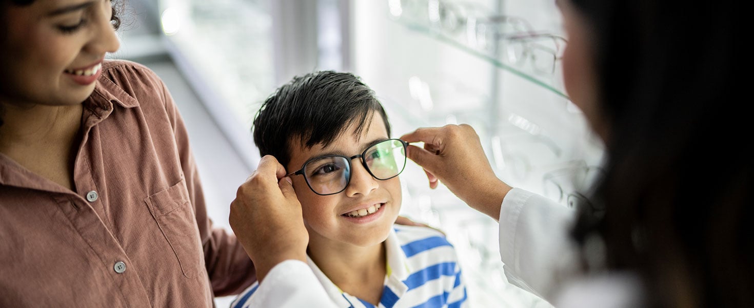 Mother and son buying a glasses and talking with optician at optics Credit:FG Trade Latin