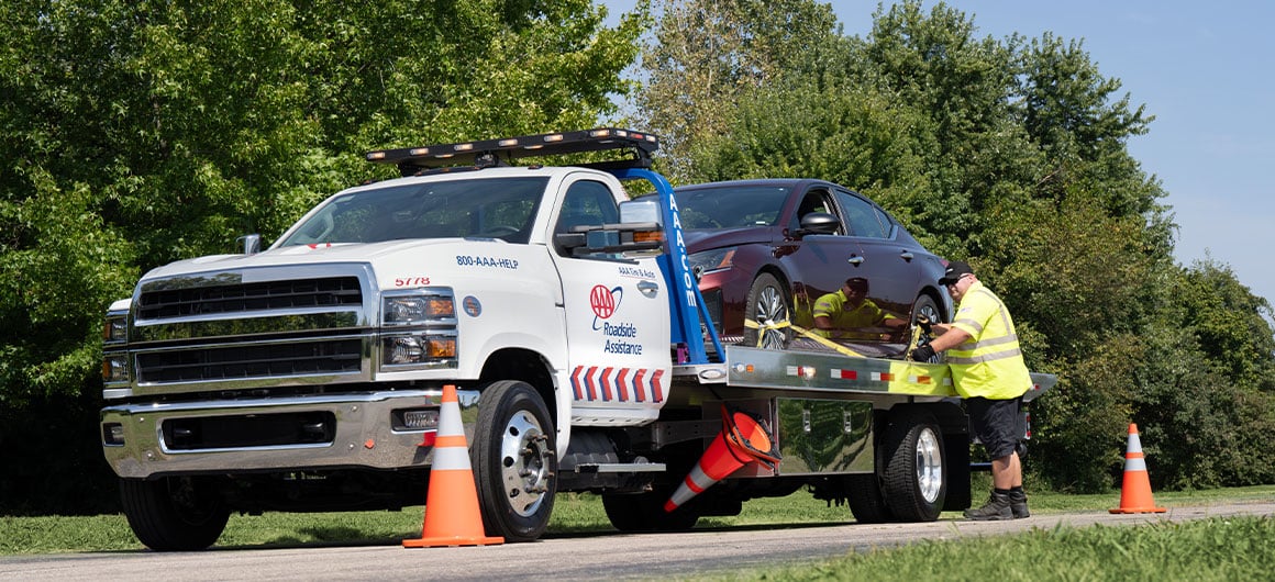 Worker securing car to AAA Roadside Assistance tow truck