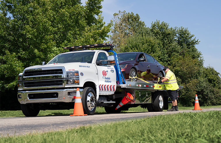 Worker securing car to AAA Roadside Assistance tow truck