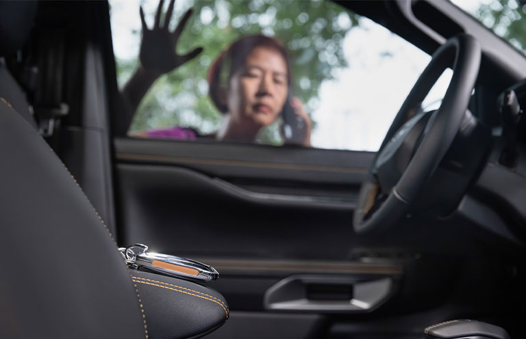 woman looking through car windows at car keys locked inside