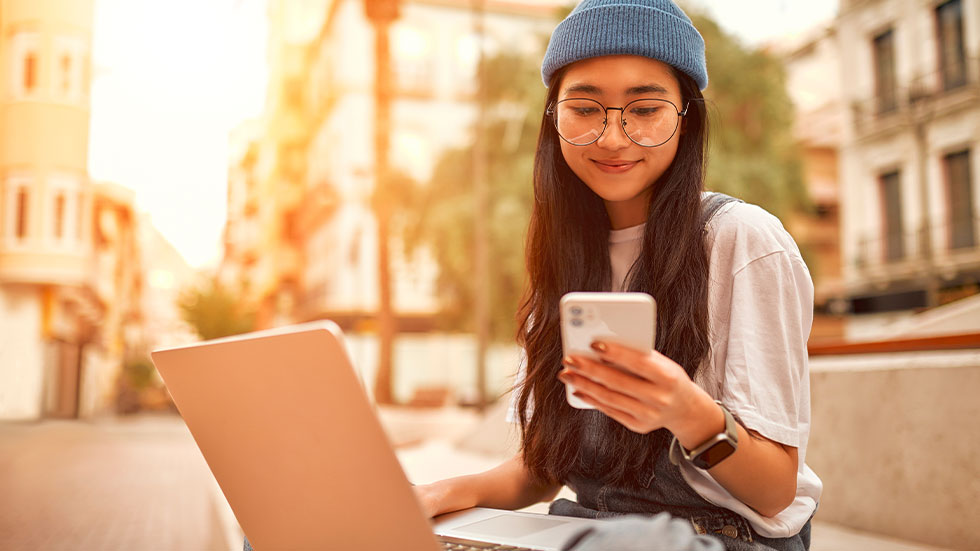 teenager wearing glasses while on phone and laptop