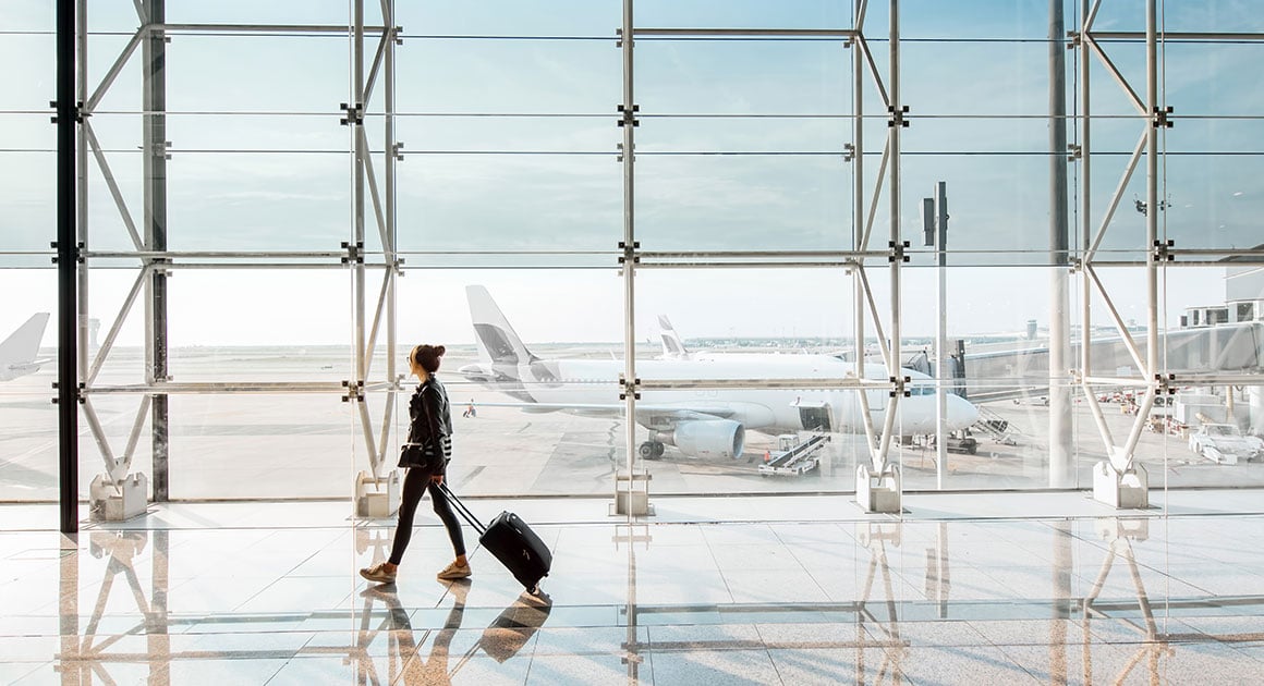 woman walking in airport with suitcase