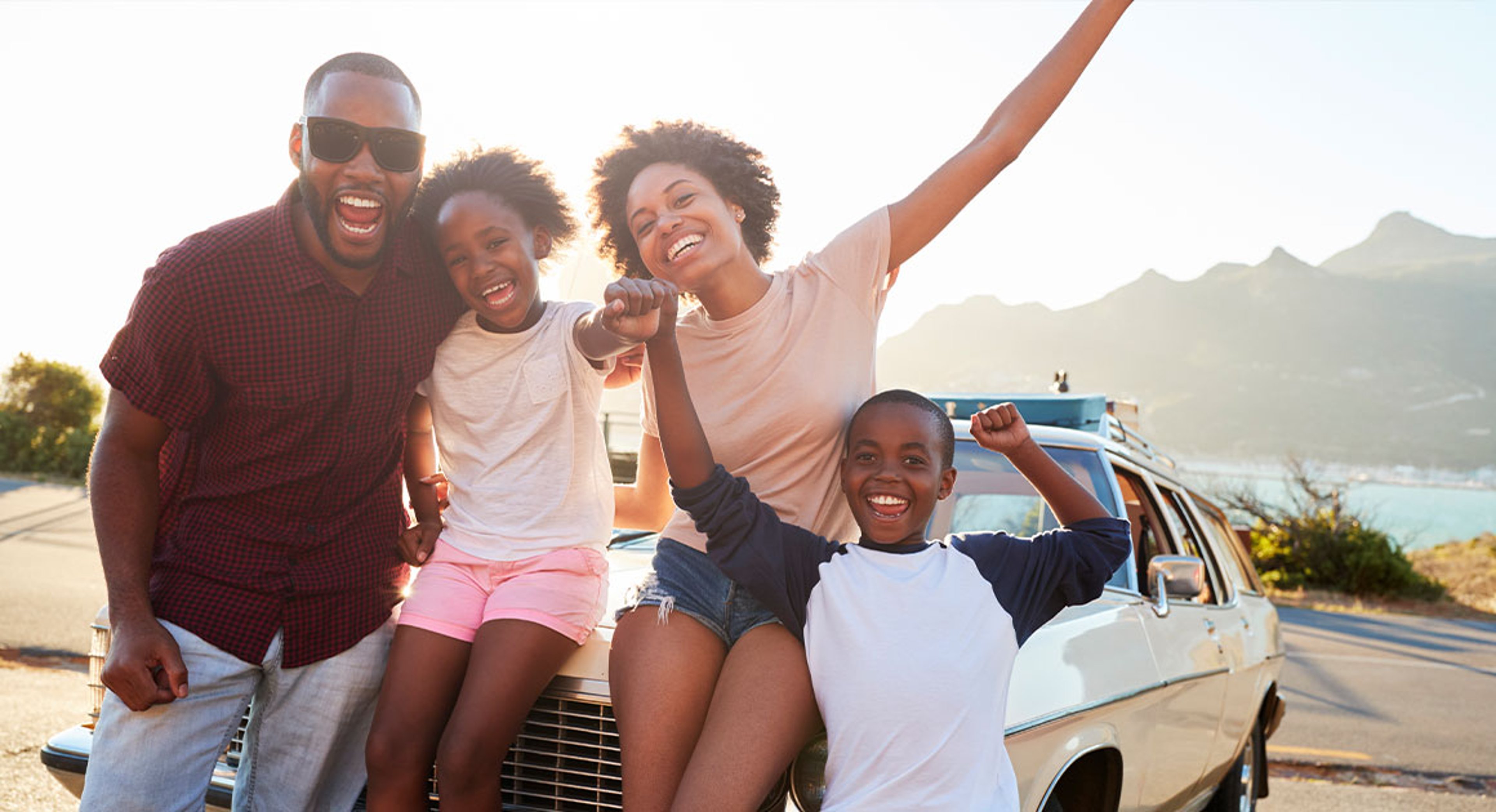 Family posing on hood of car