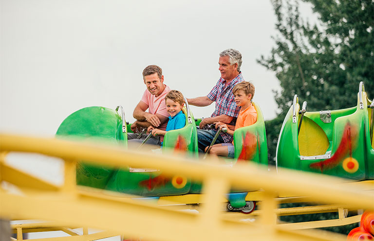father, grandfather, and children on roller coasters