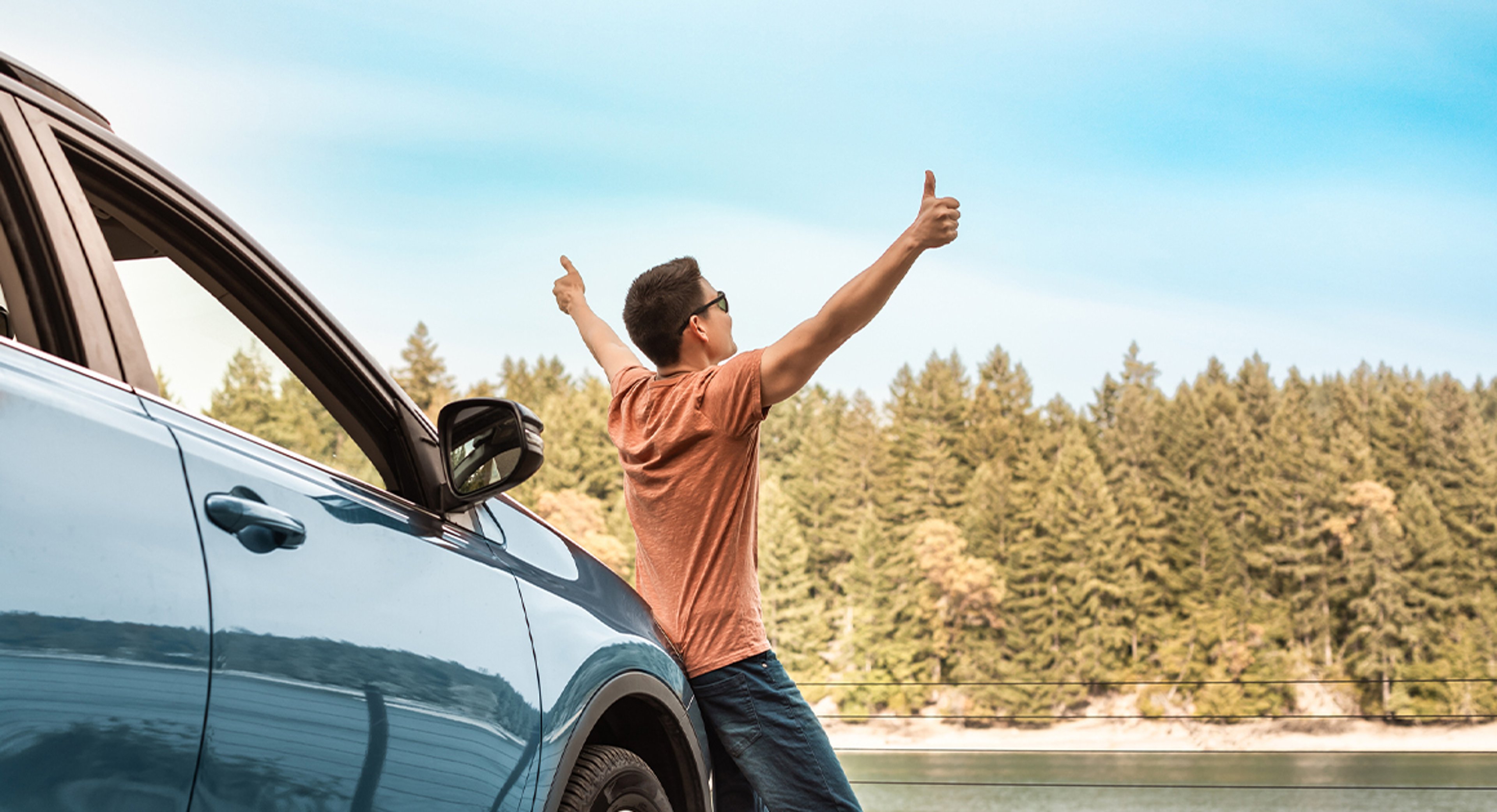 man standing in front of parked car with thumbs up looking at view