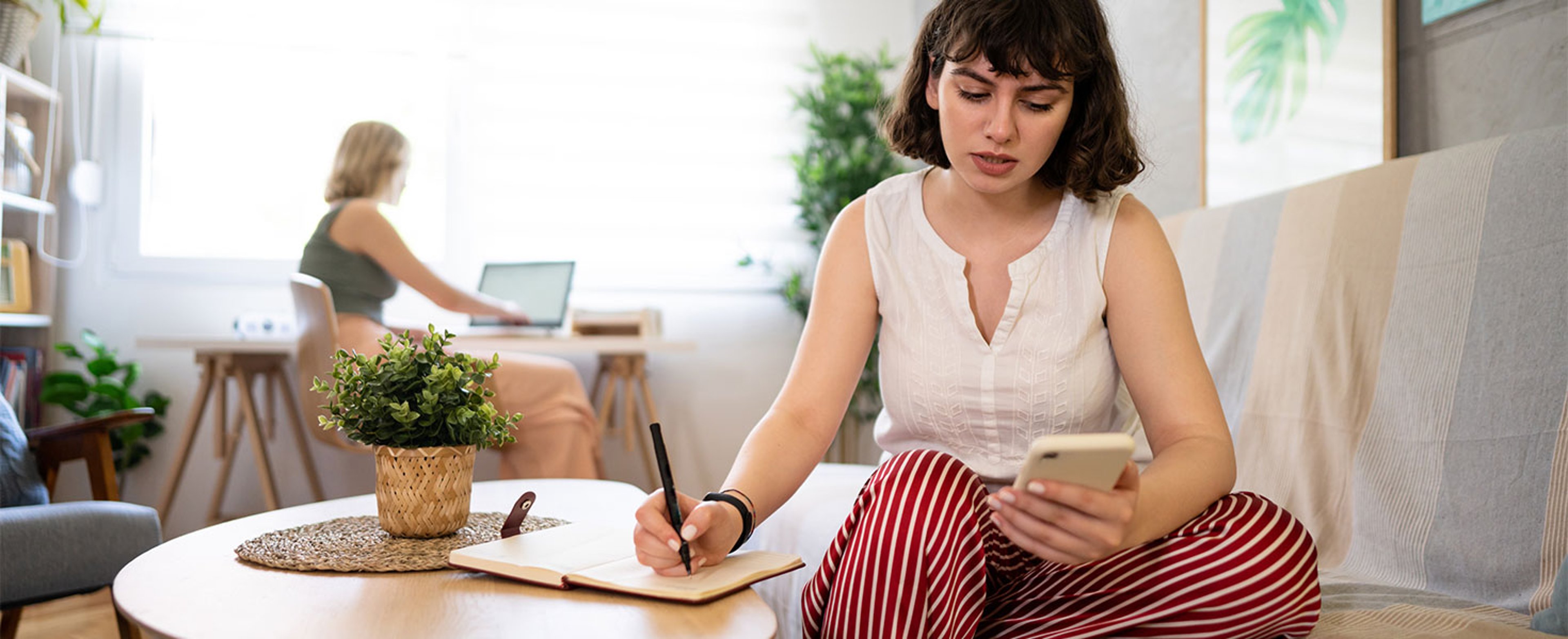 girl looking at phone and taking notes
