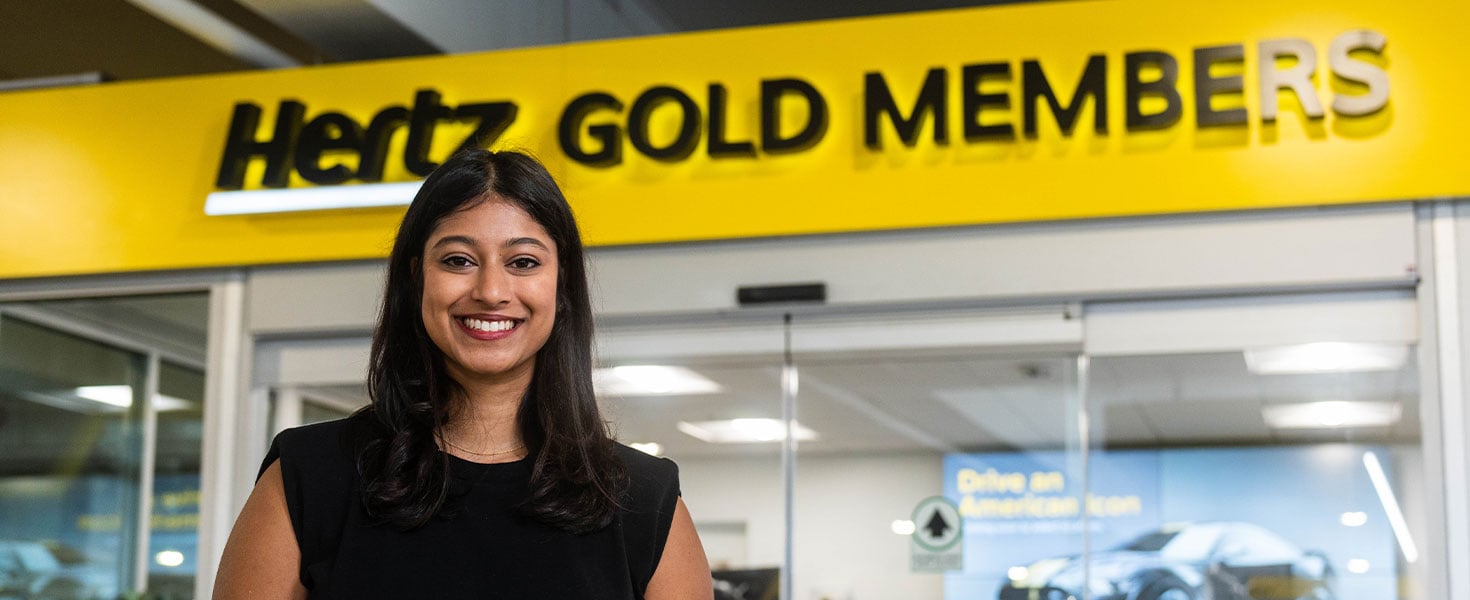 Woman standing in front of Hertz Gold Members sign