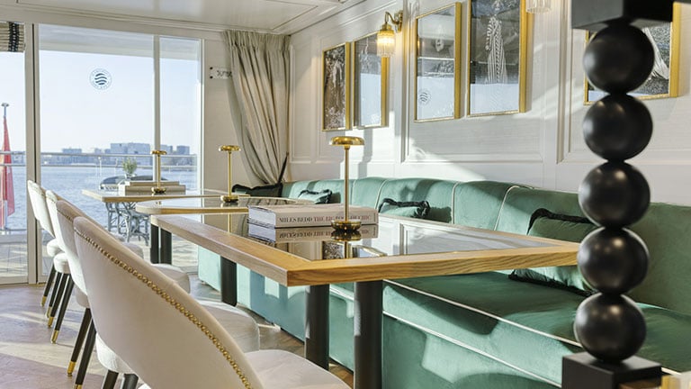 Cushioned lounge chairs beside floor-to-ceiling windows overlooking the Danube River and Budapest.