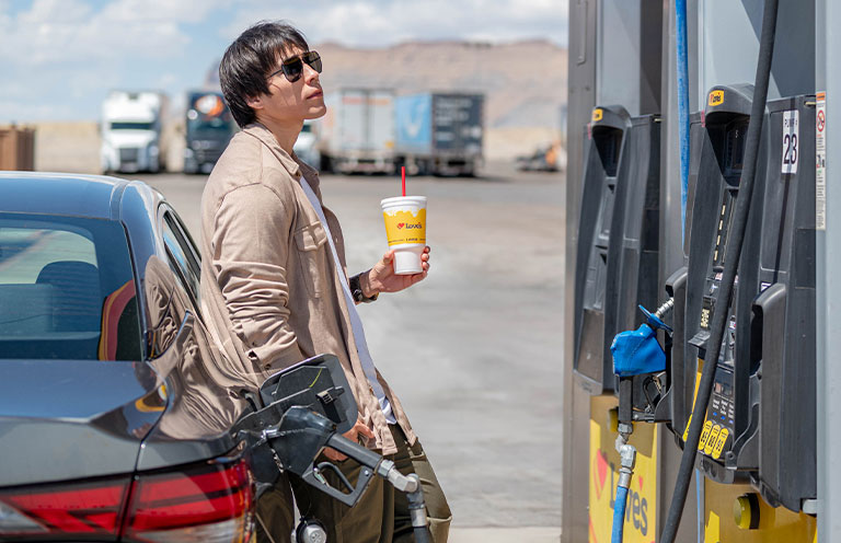 man filing gas tank holding soda cup from Loves