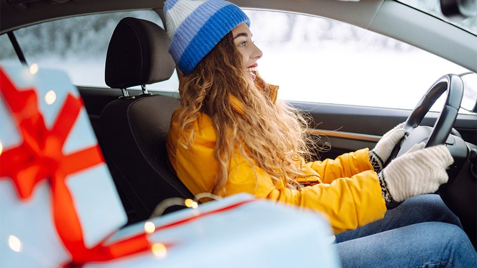 woman driving car with presents in passenger seat