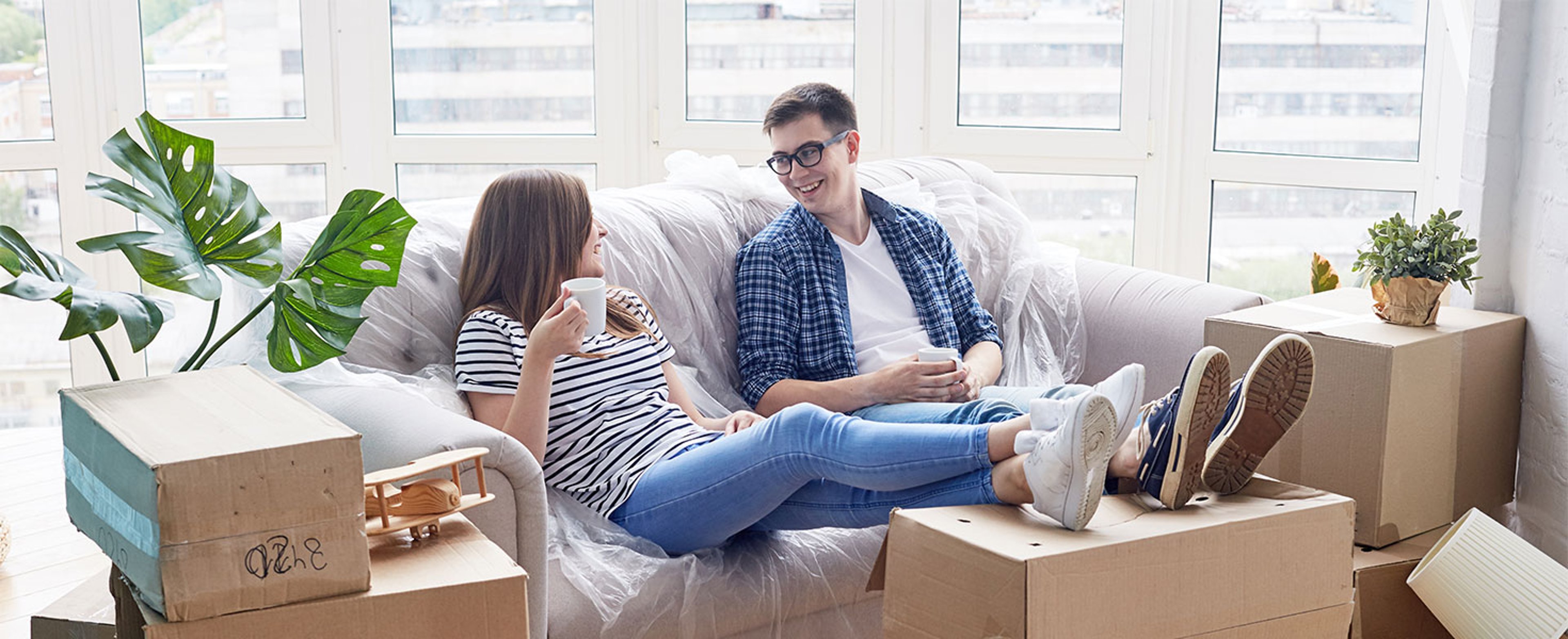 man and woman relaxing on couch with moving boxes around them