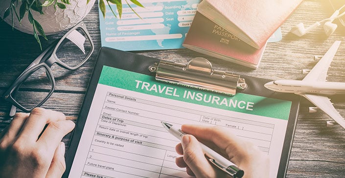 A desk with a travel insurance form, glasses, passport, boarding pass, and a model airplane.