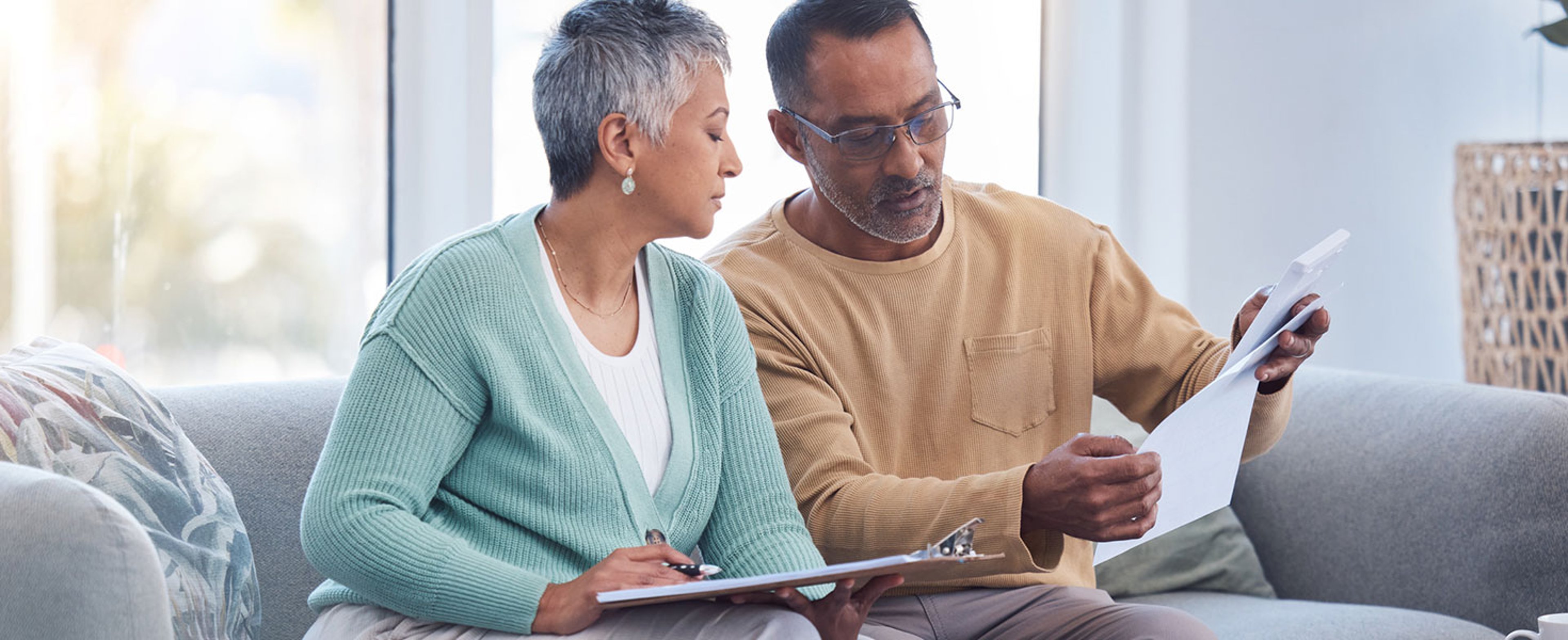 Finance, documents and senior couple on sofa with bills, paperwork and insurance checklist in home, life or asset management, Elderly black people on couch with financial, retirement or mortgage debt. Photo by PeopleImages