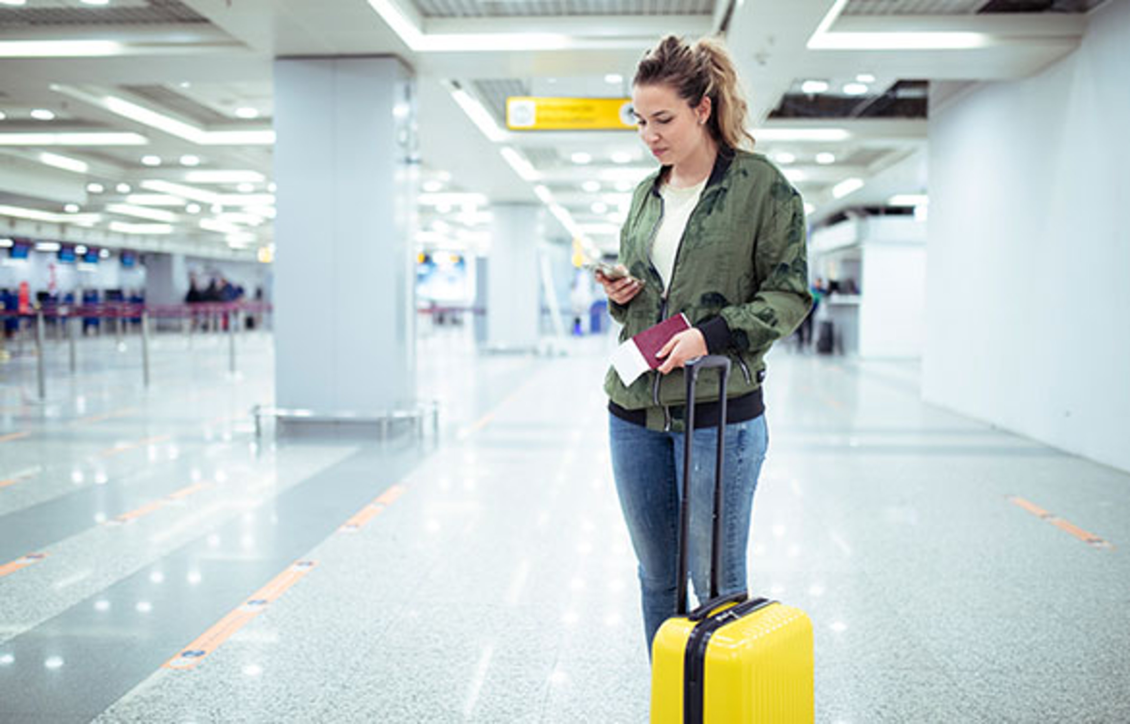 Woman waiting with yellow suitcase after delayed flight