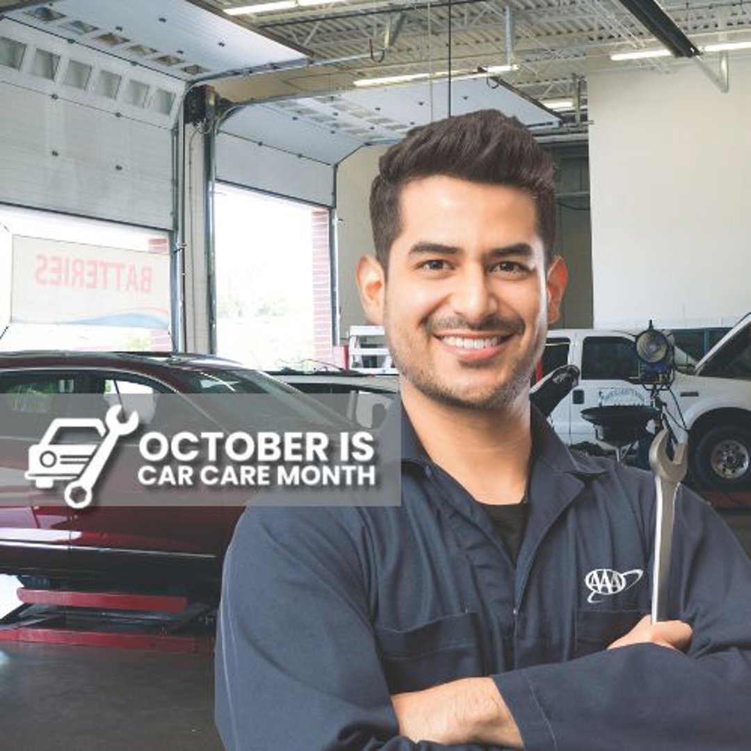 Smiling auto technician with arms folded with superimposed October car care month