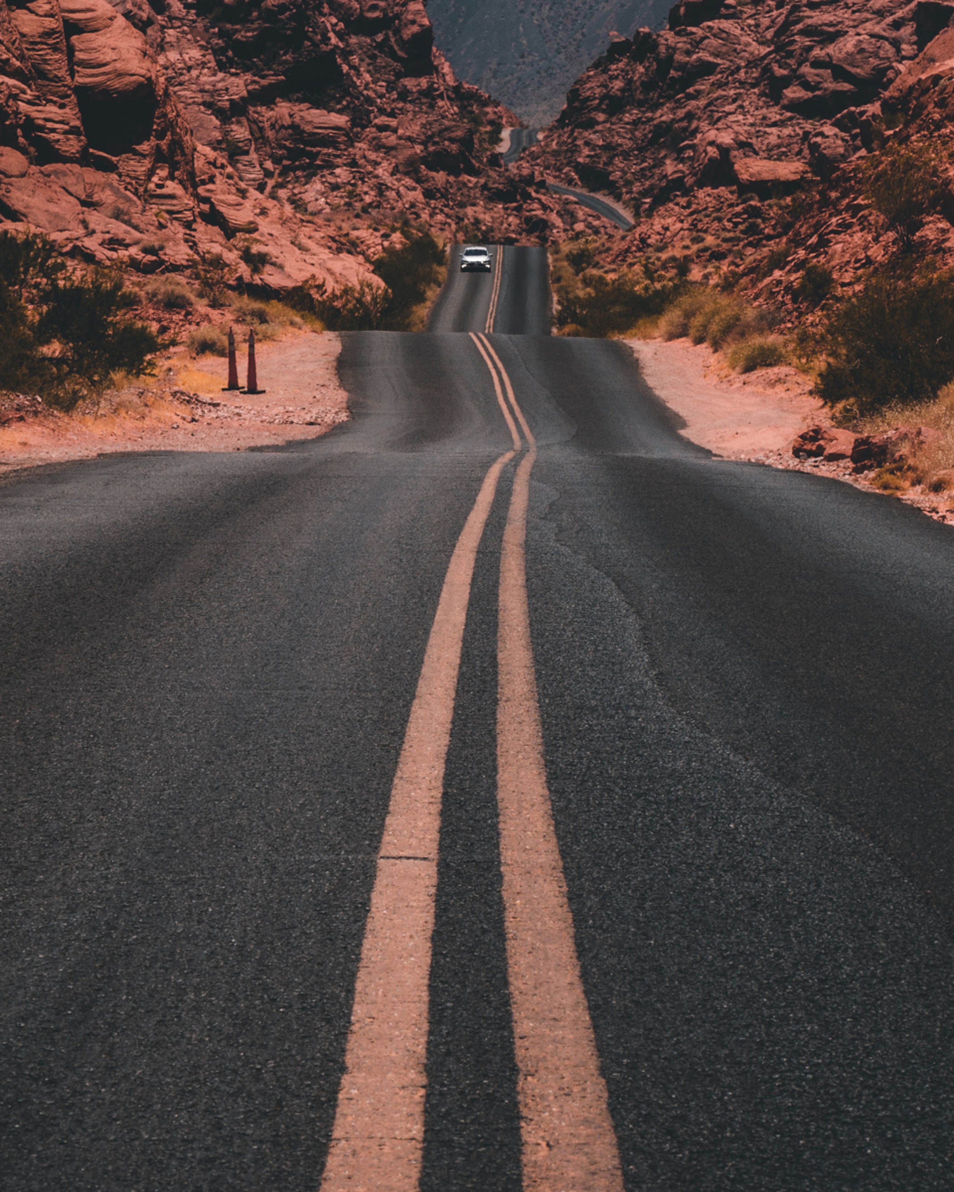 Car traveling down winding desert highway surrounded by rock formations in Valley of Fire State Park