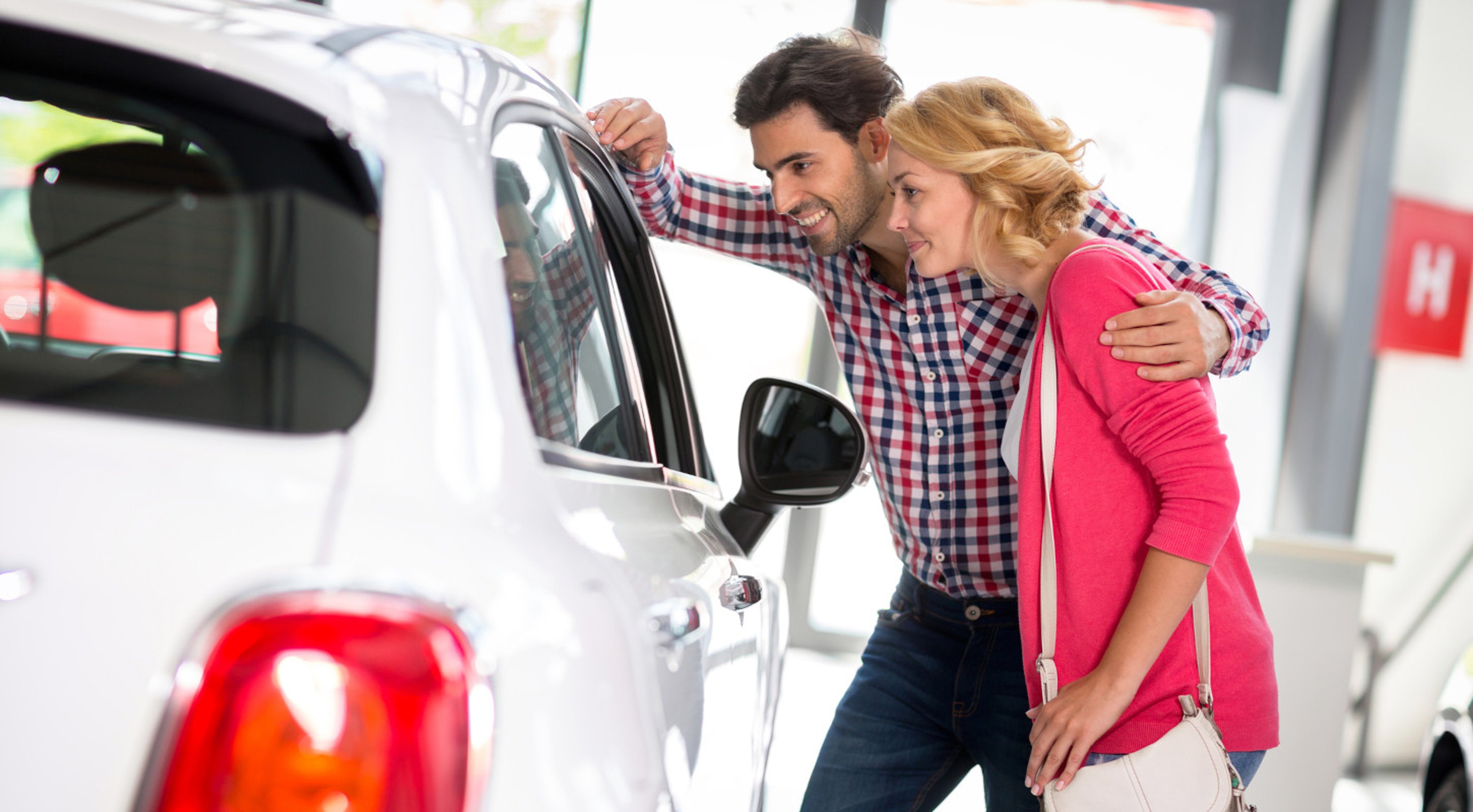 Smilng couple buying a white vehicle at car dealership