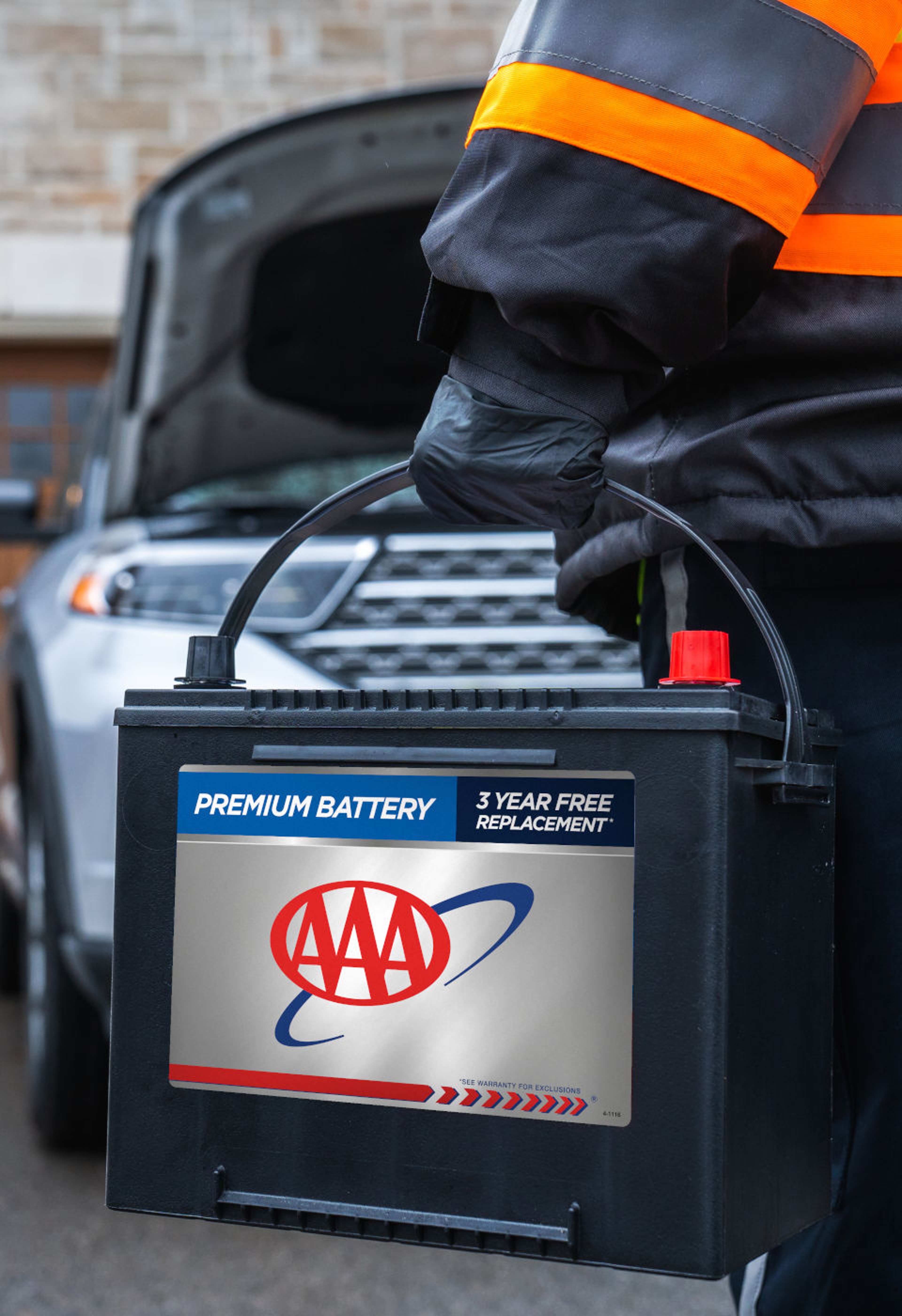 AAA roadside assistance technician carrying premium AAA battery