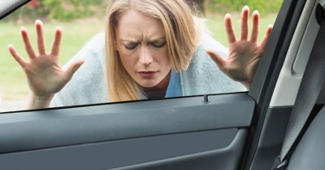 Woman looking inside locked locked car