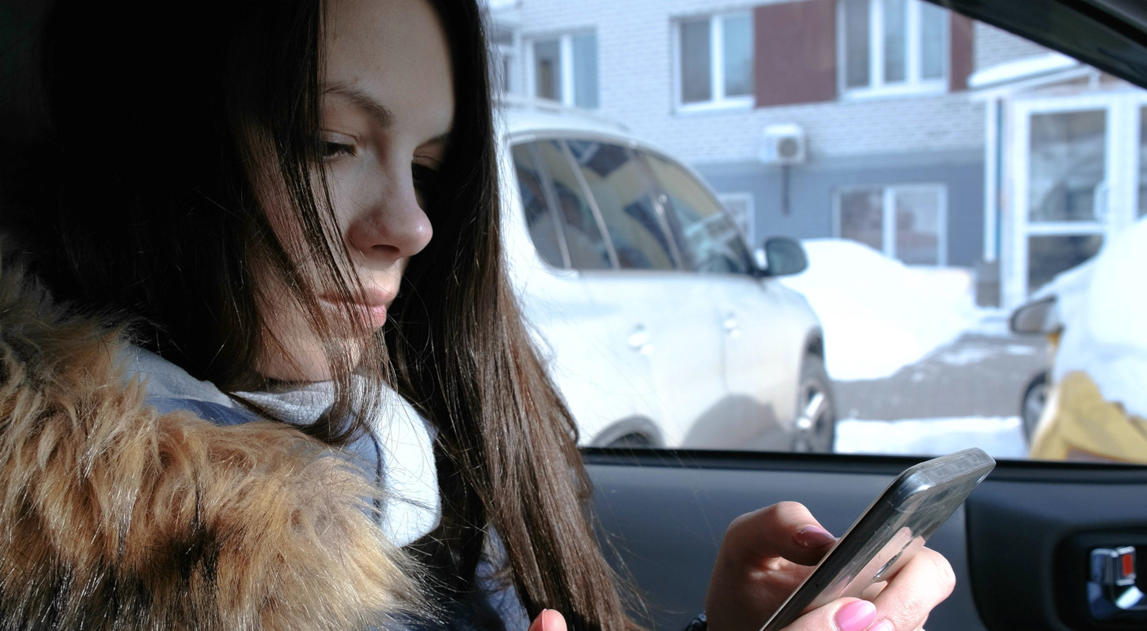 AAA Request Roadside Assistance Online Woman Car Woman in broken down car in winter contacting roadside assistance online on her smartphone
