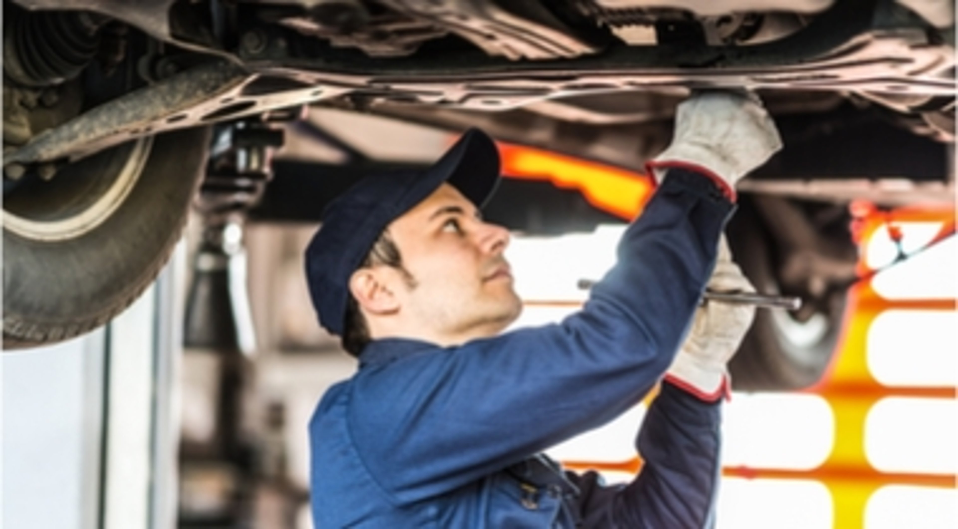 BSTS mechanic working on undercarriage of car