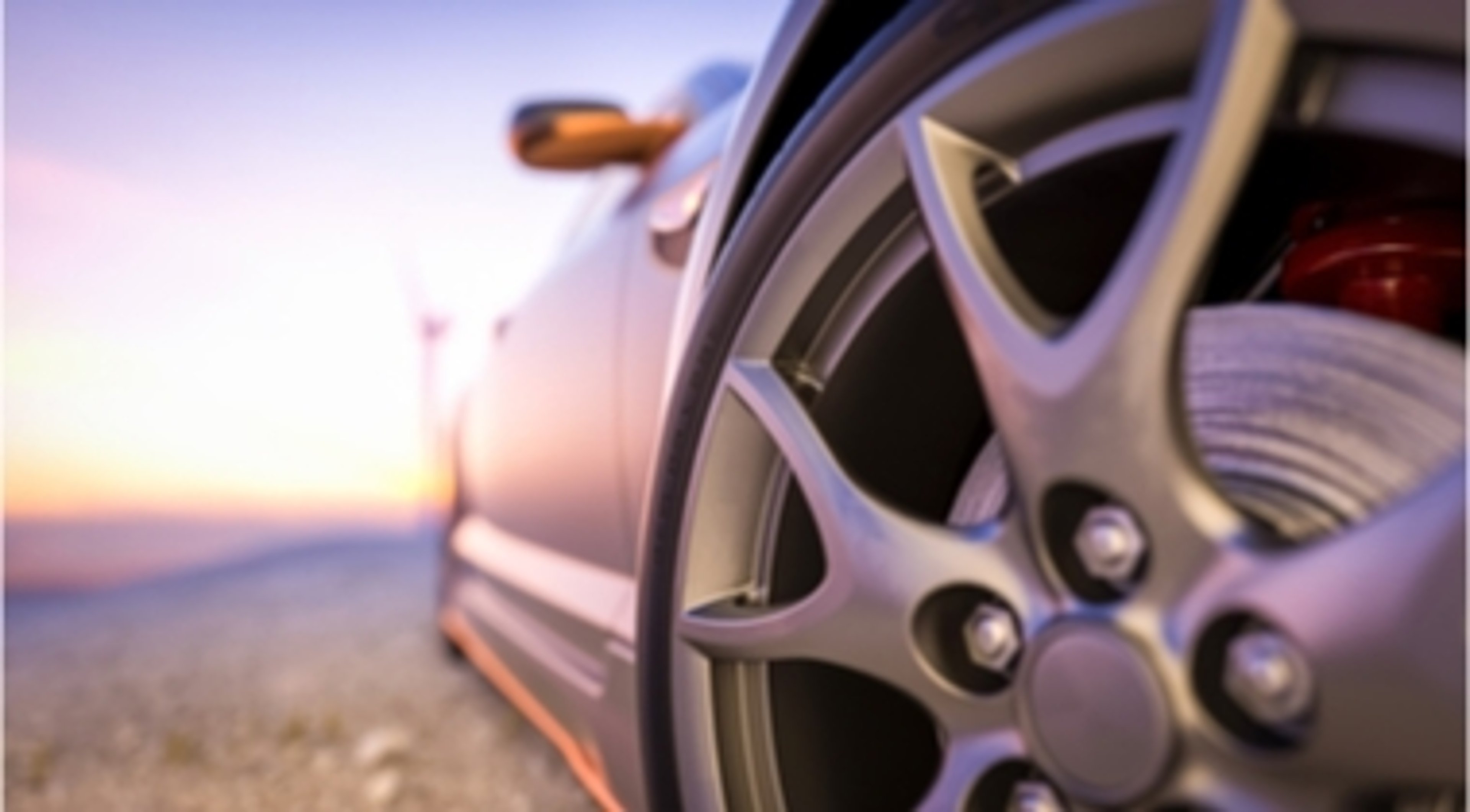 Wheel and hubcap of car with sunset in the background
