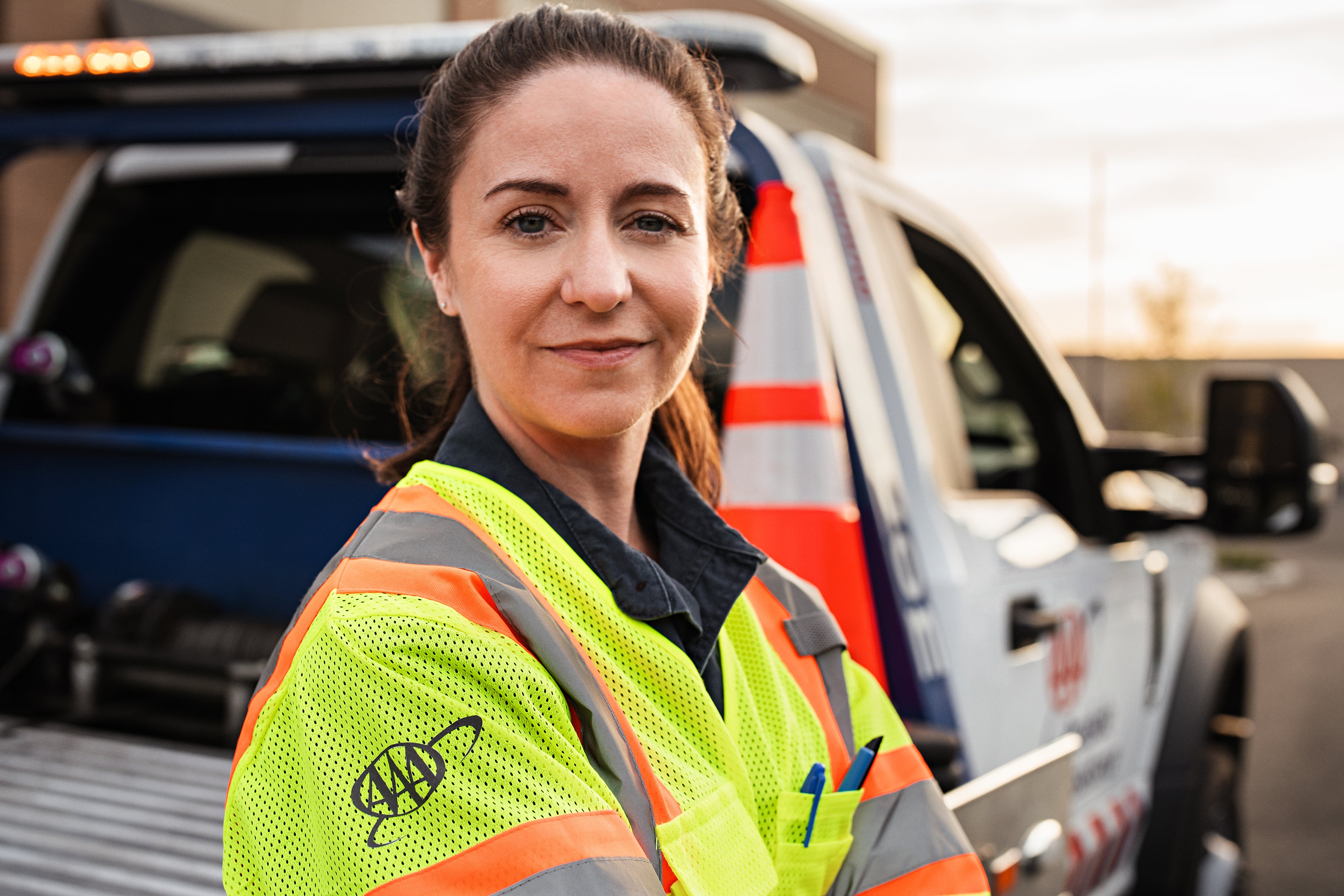 A woman car technician posing against a branded truck 