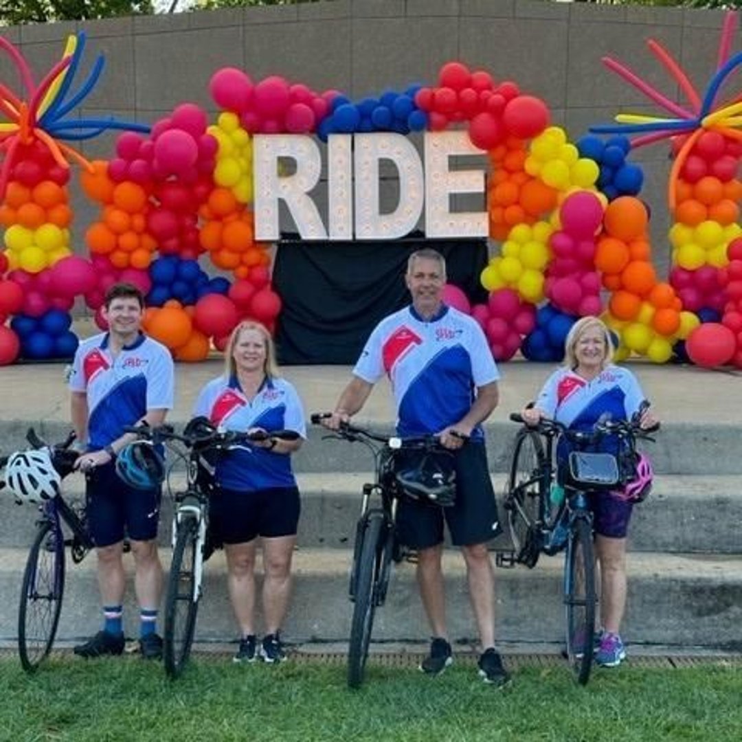 AAA Ride Cincinnati family standing with bicycles in front of balloon arch