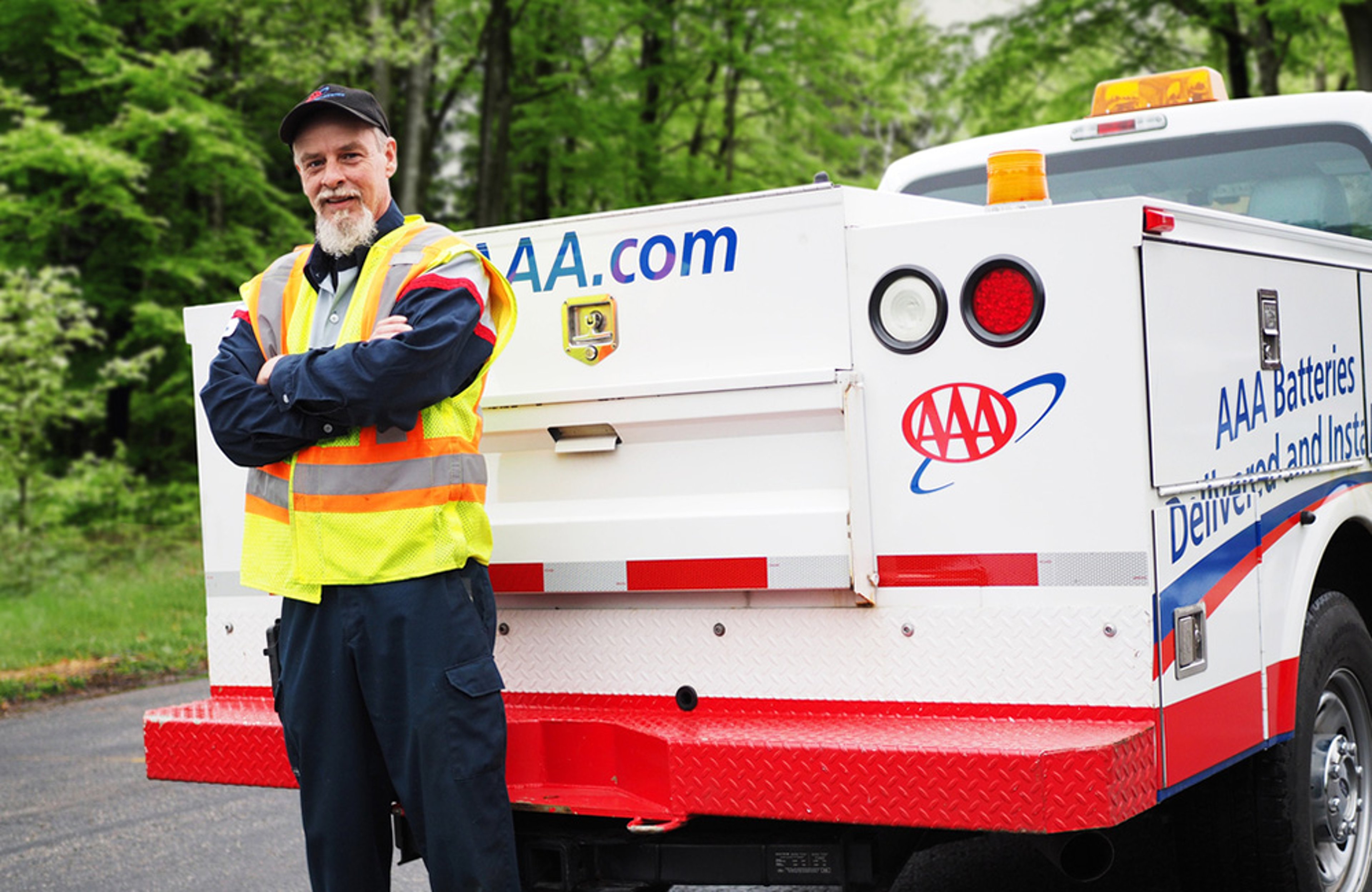 AAA Roadside Assistance technician standing and smiling next to his service truck