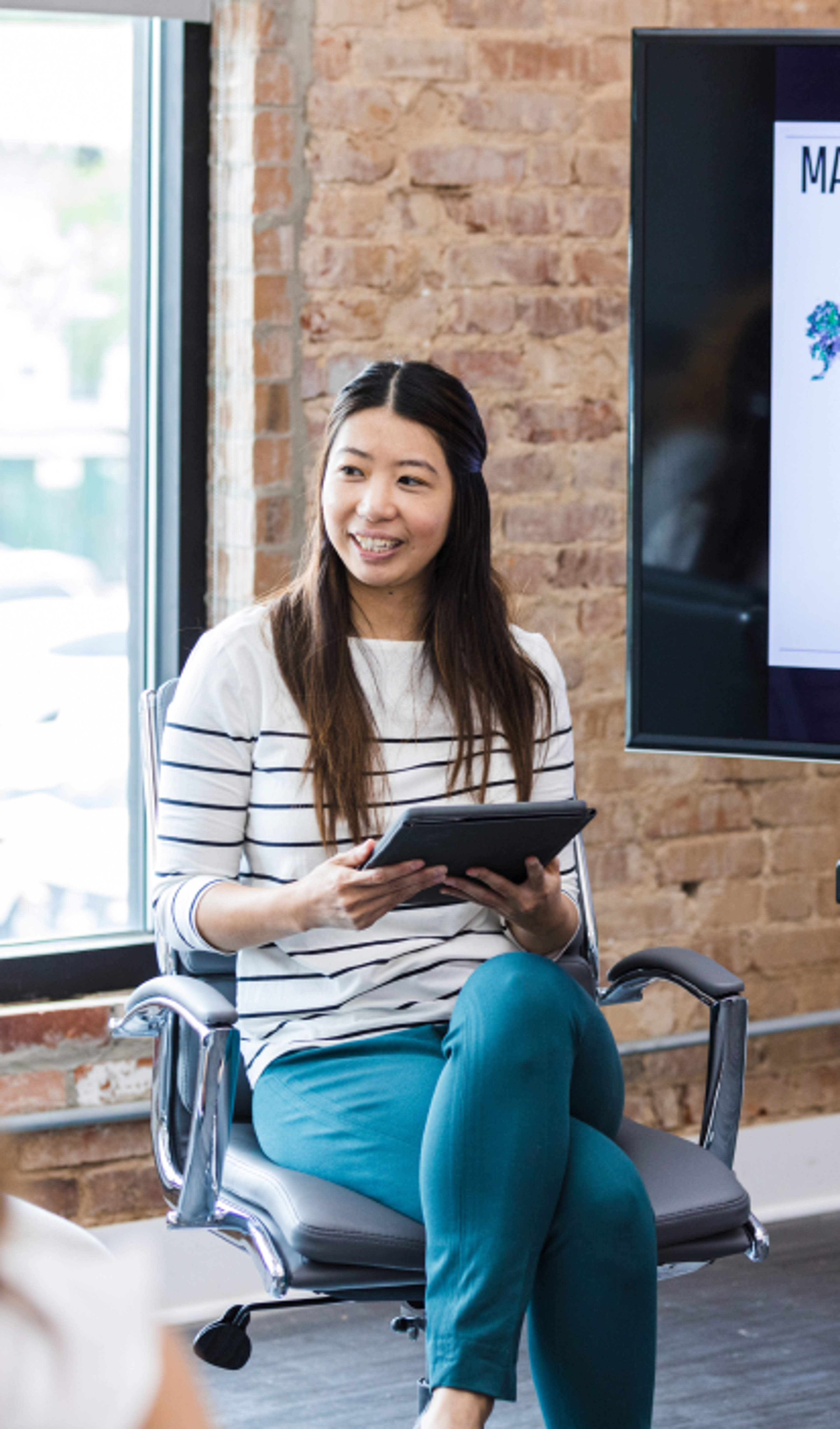 Smiling woman sitting in front of brick wall reading a magazine