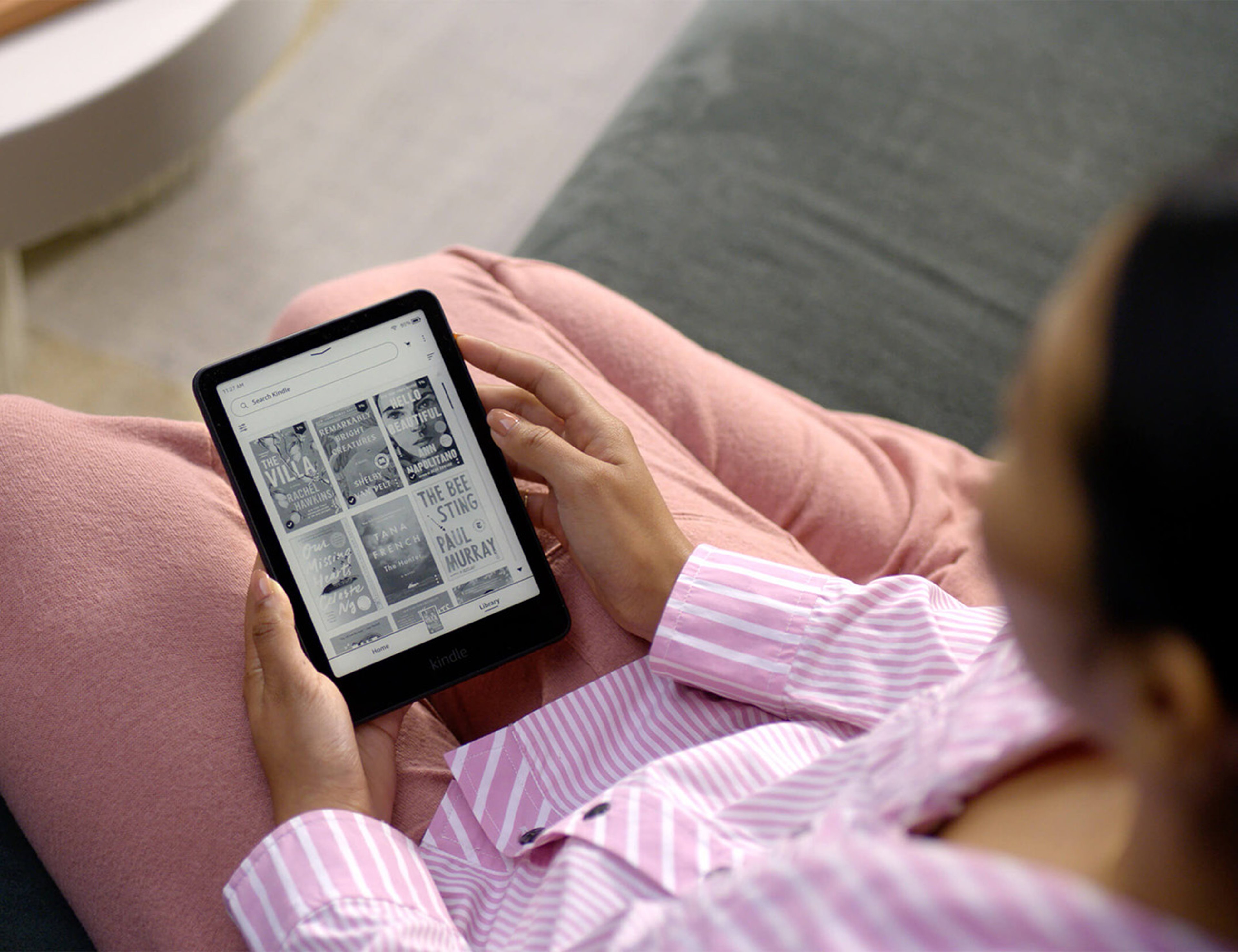 Girl in striped pink shirt choosing from list of ebooks on Kindle Paperweight