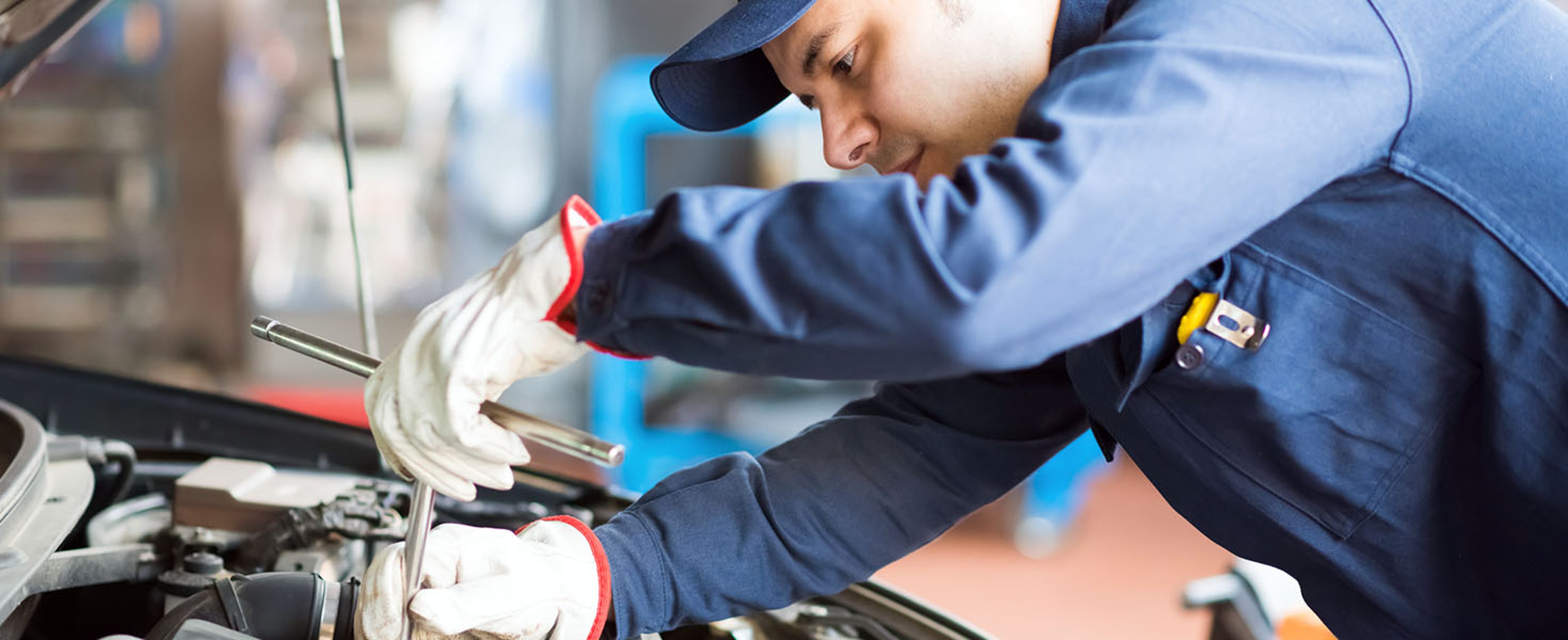 Auto repair mechanic under car hood working on engine