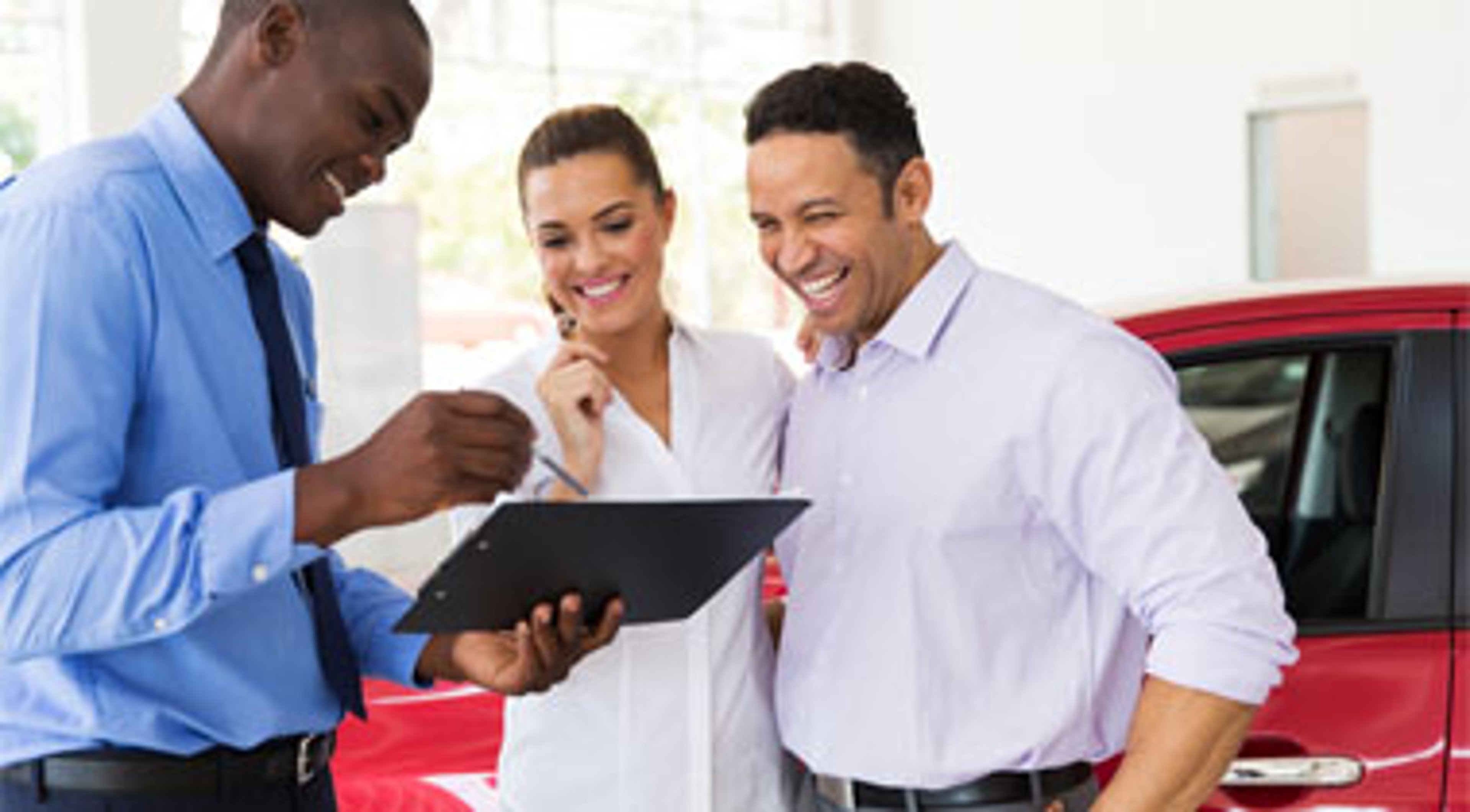 Car dealer explaining contract to couple buying a car