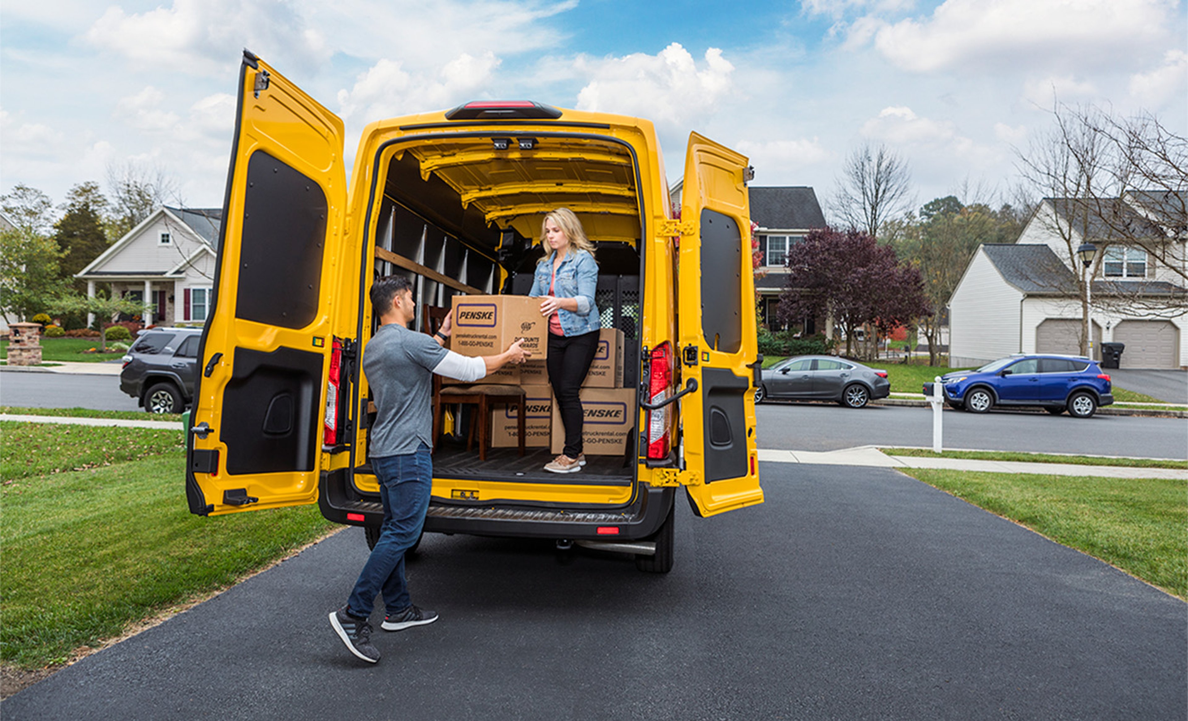 Couple carrying boxes out of yellow moving van