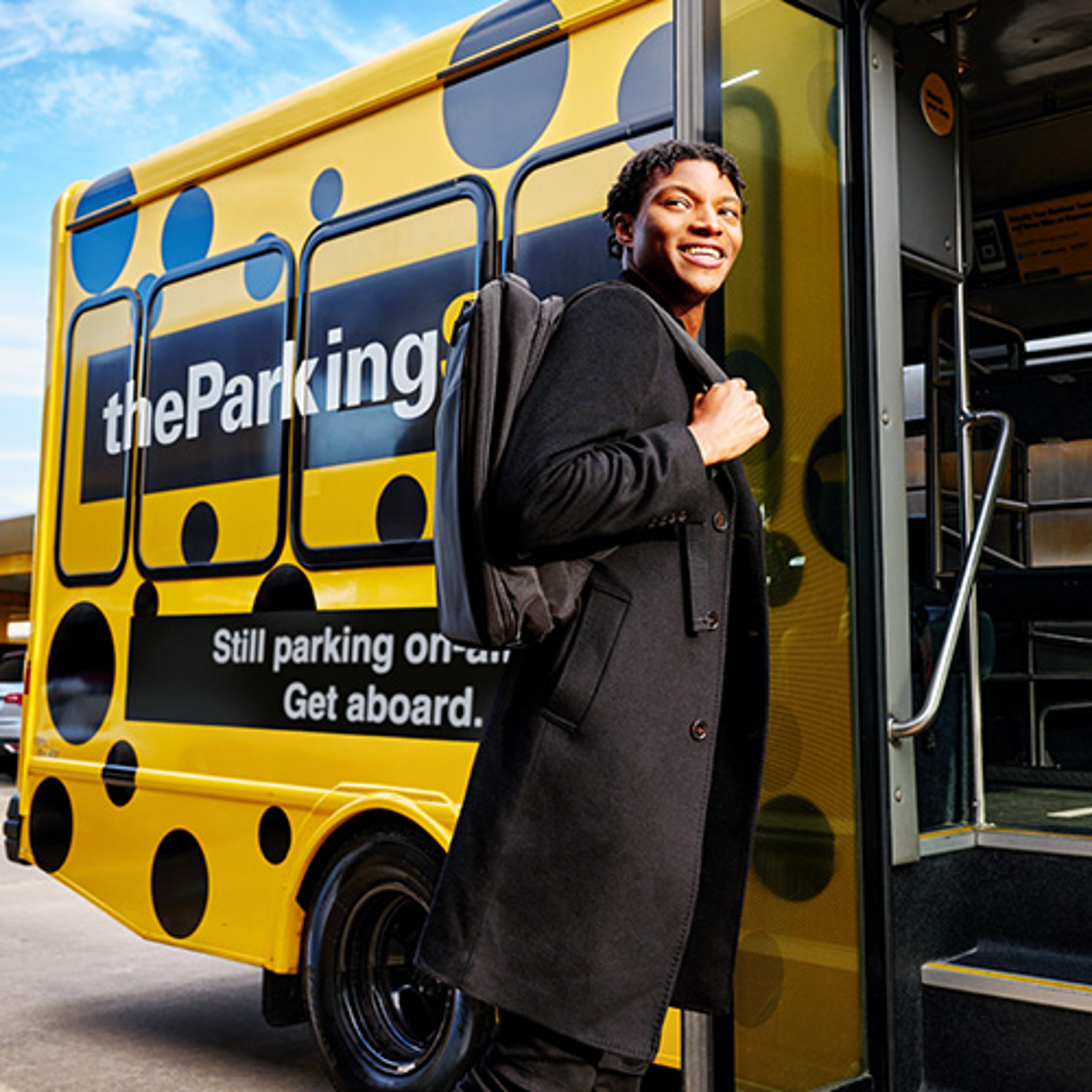 Woman in long black coat smiling as she is about to board the Parking Spot shuttle