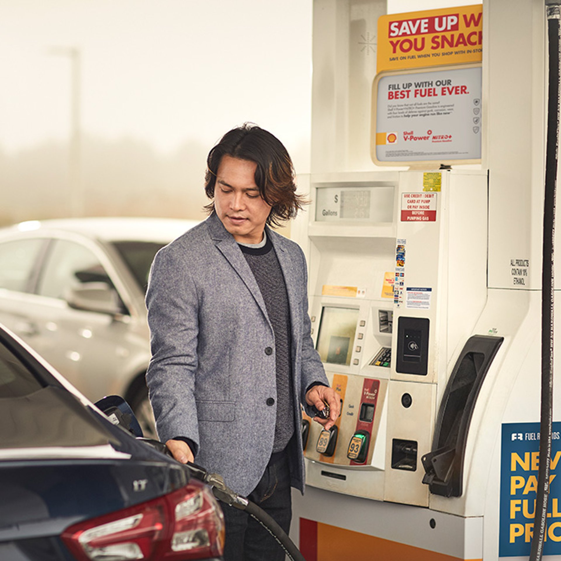 Businessman in blazer fueling up at Shell gas station 