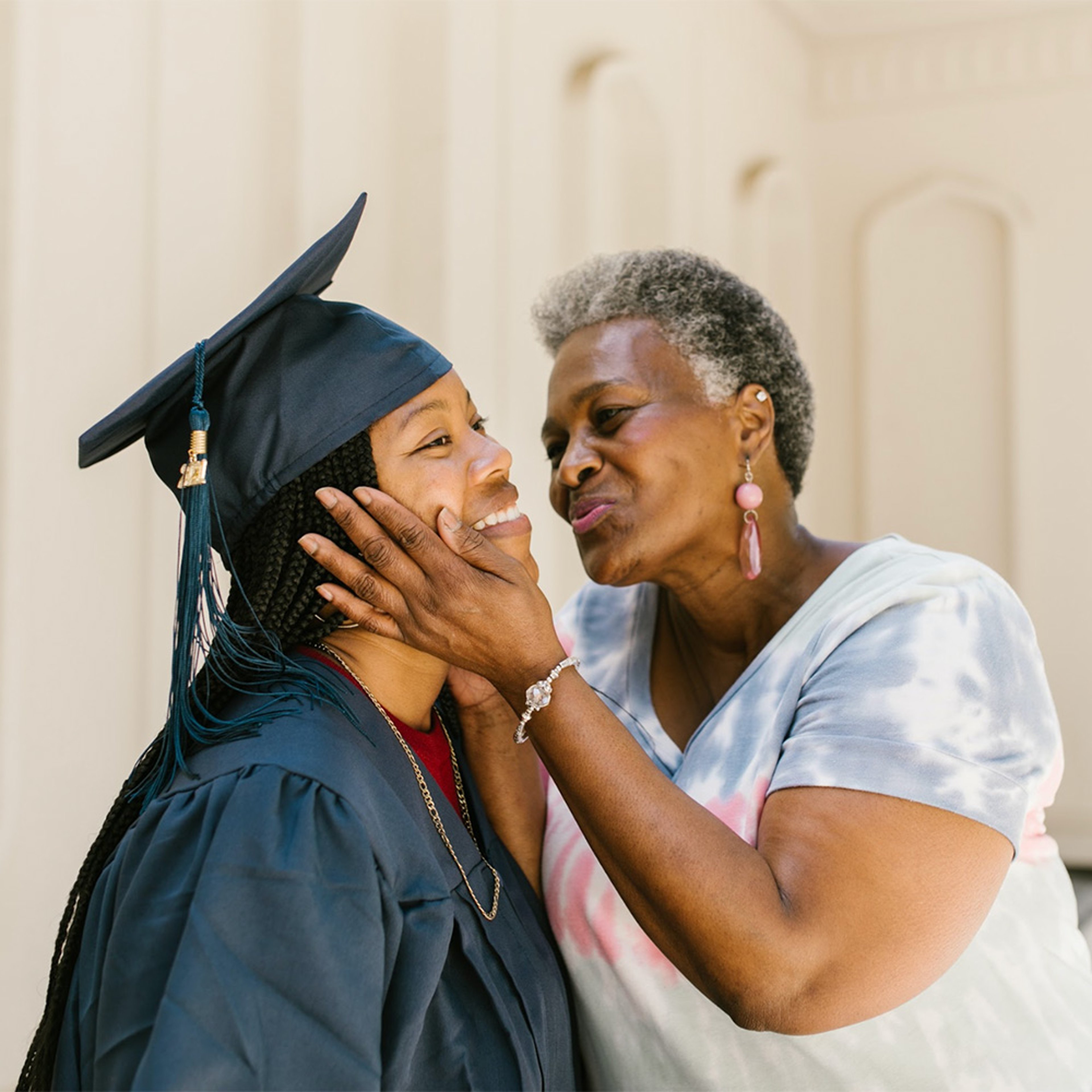 Grandmother leaning over to kiss graduate's cheek