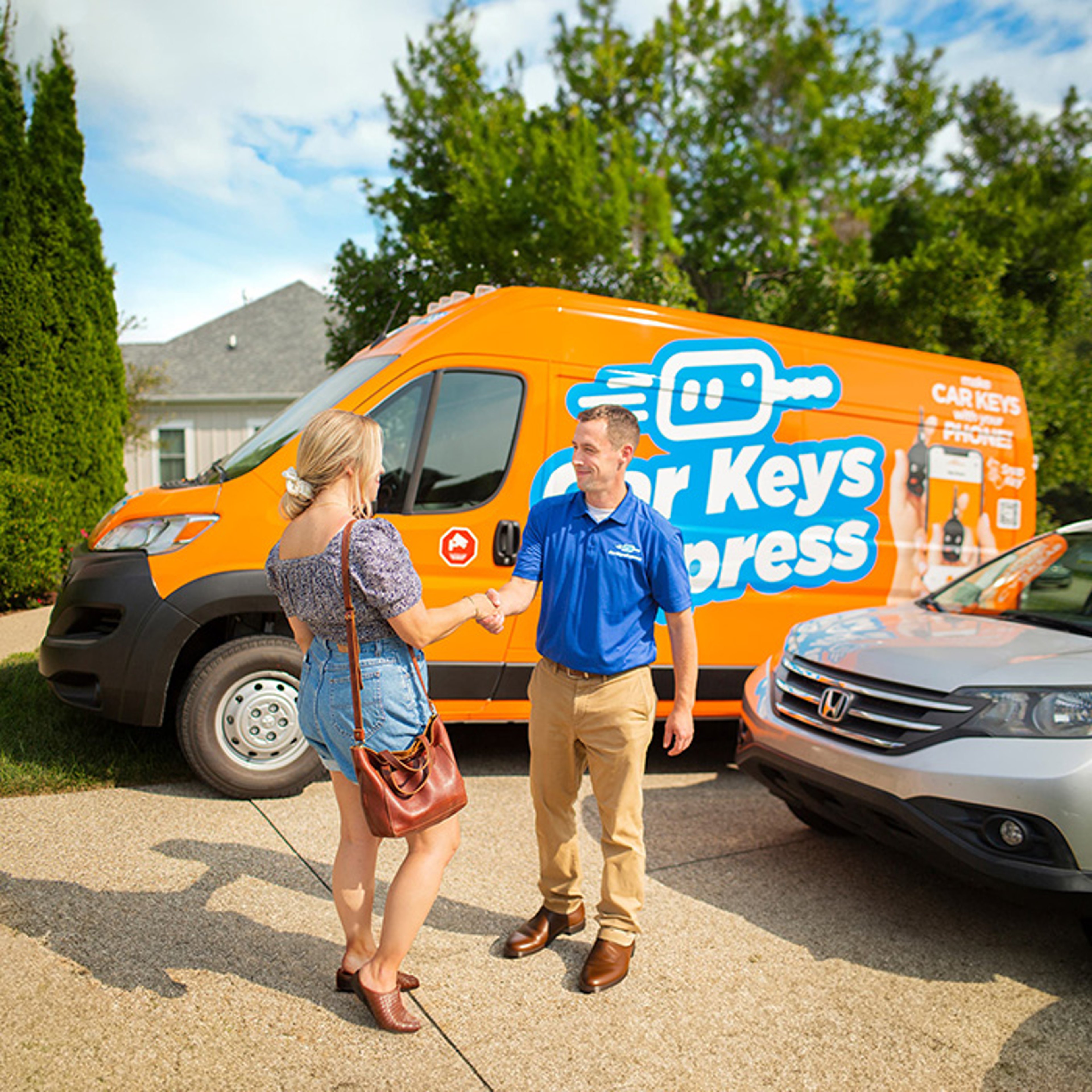Car Keys Express technician standing in front of service truck handing customer keys in her driveway after lockout