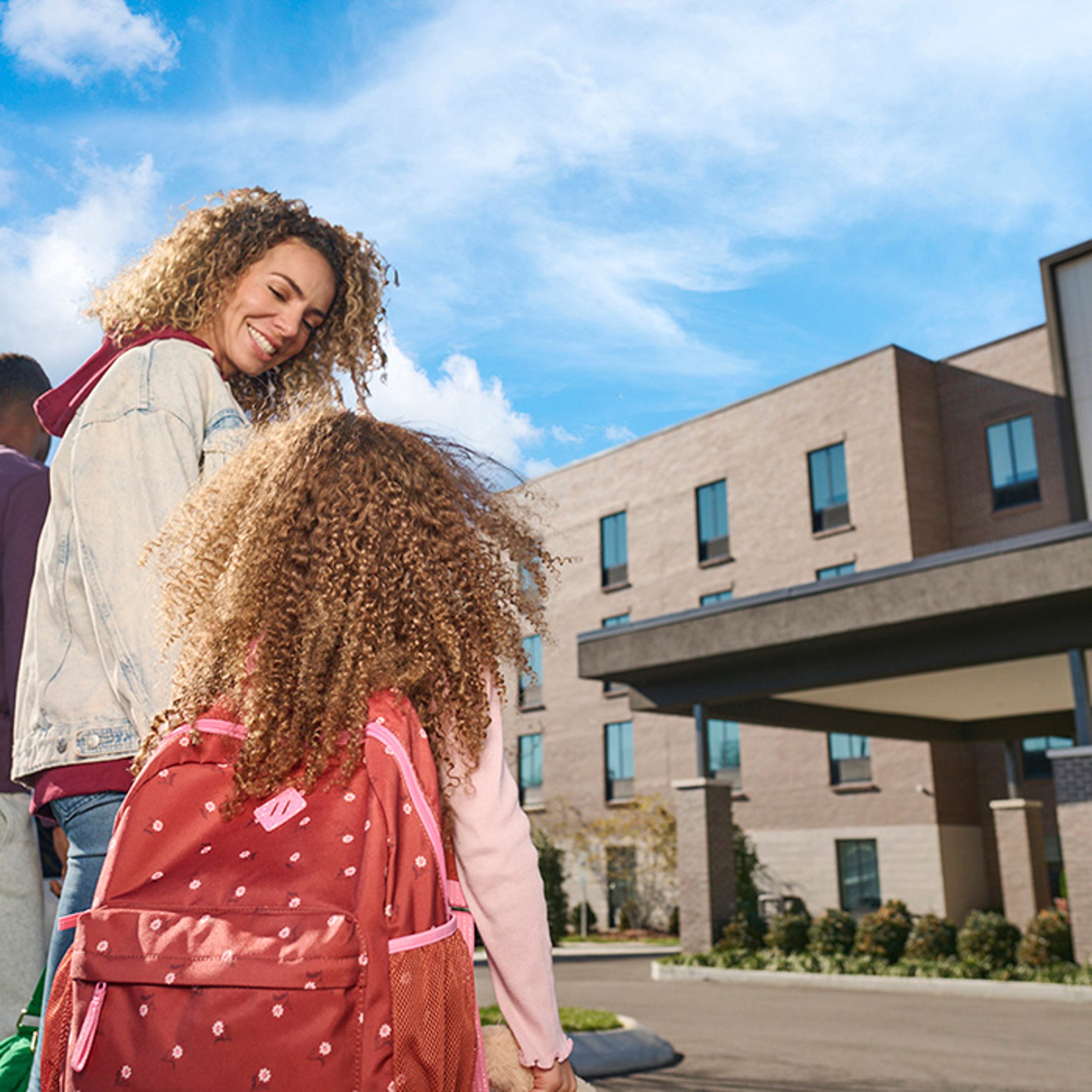 Mother and daughter smiling as they walk through parking lot of Choice Hotel location