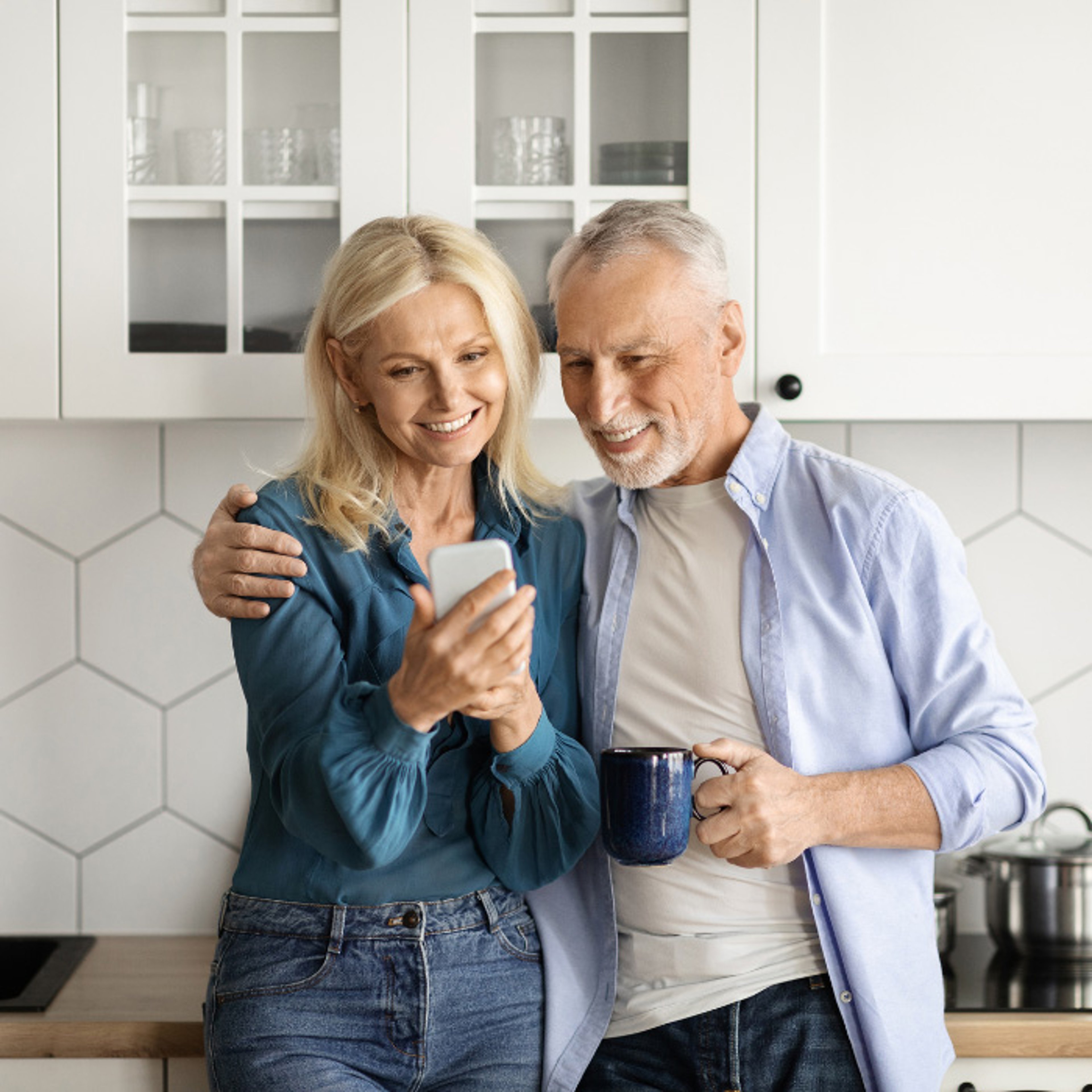 Smiling older couple looking at phone in kitchen